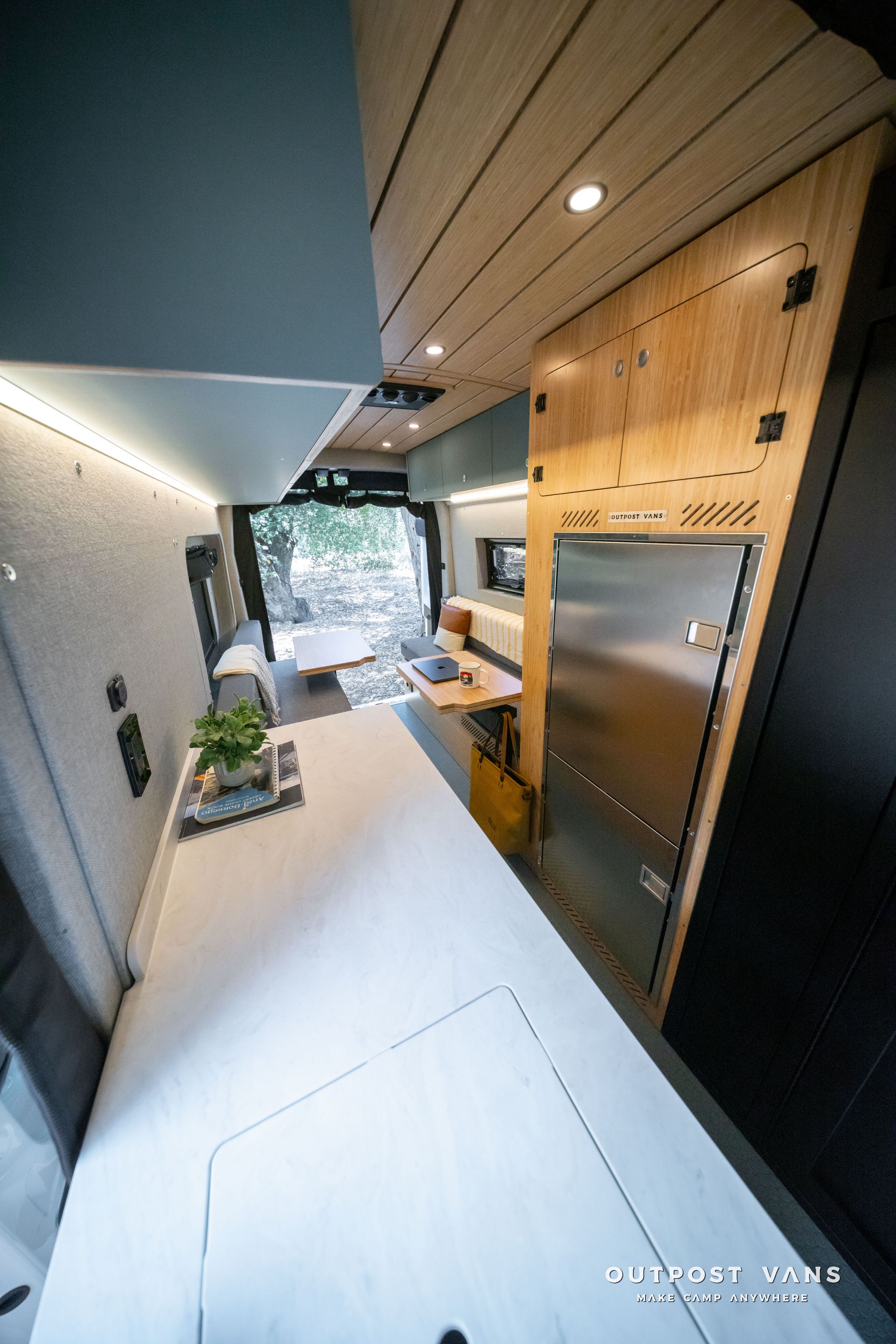 Modern minimalist hallway with wood ceiling, black walls, white floor, and a view to a bright outdoor doorway