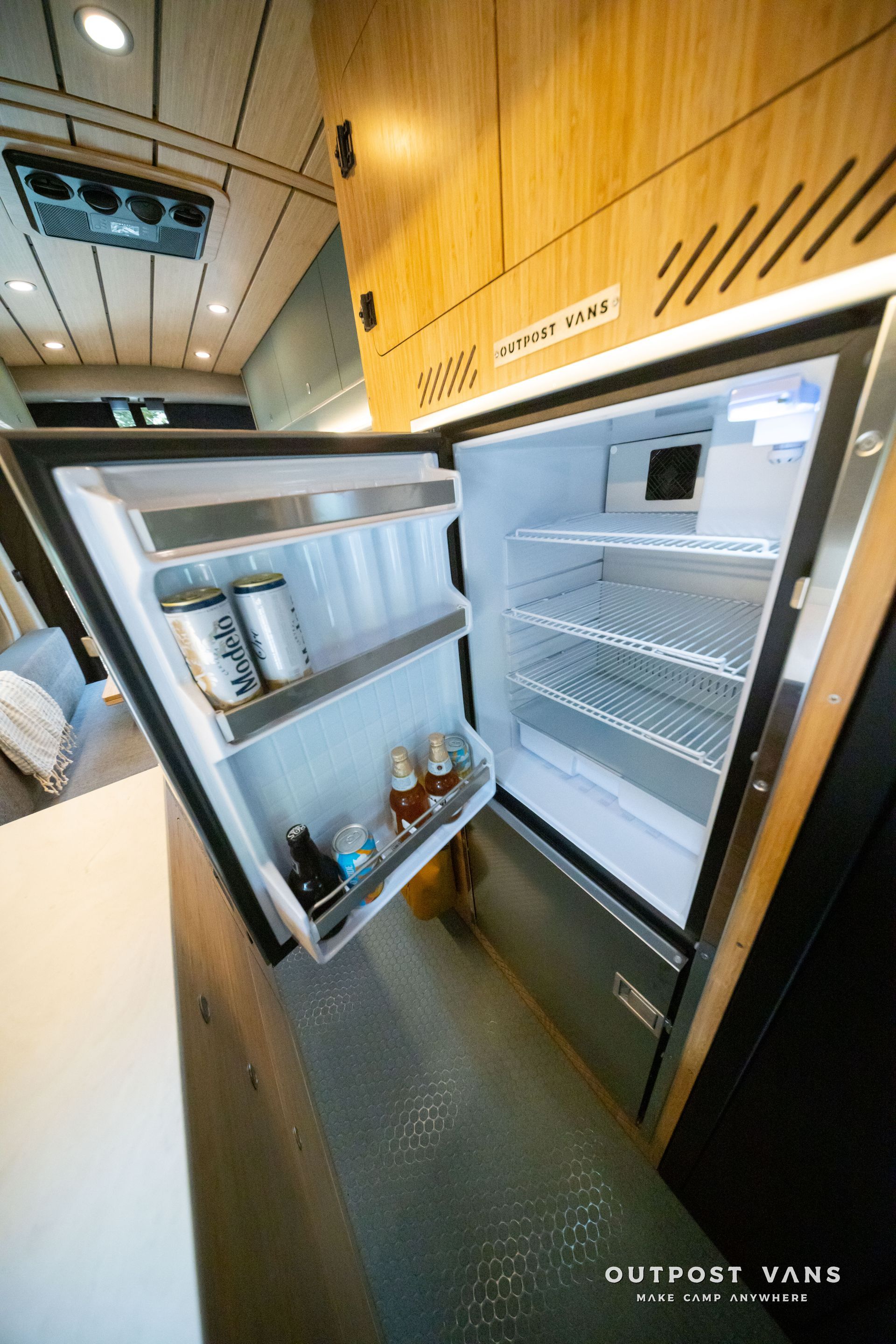Open mini fridge in a wood-paneled room, showing shelves with drinks and condiments.