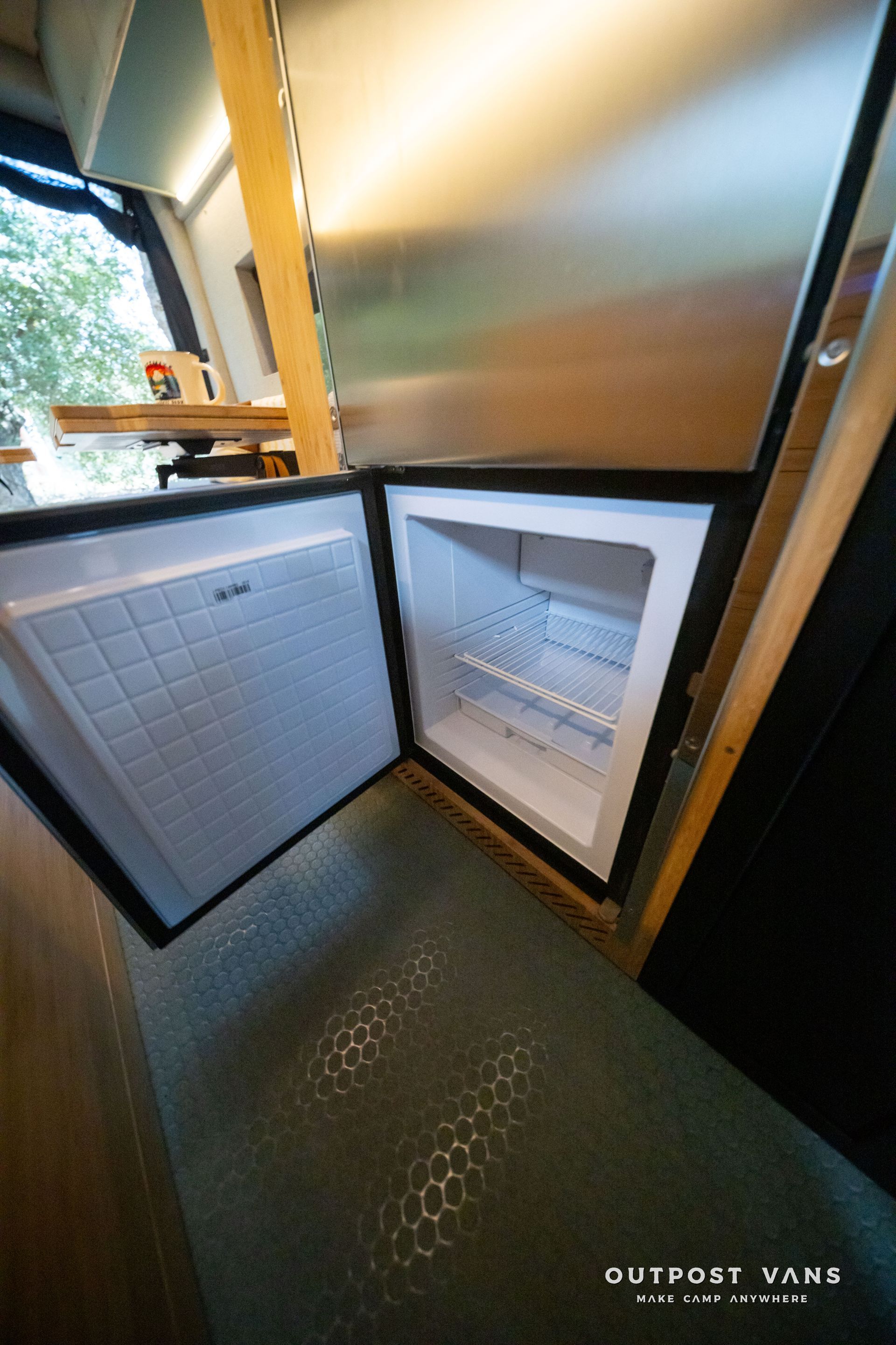 Open mini fridge under a counter, with white shelves and a metallic panel above.