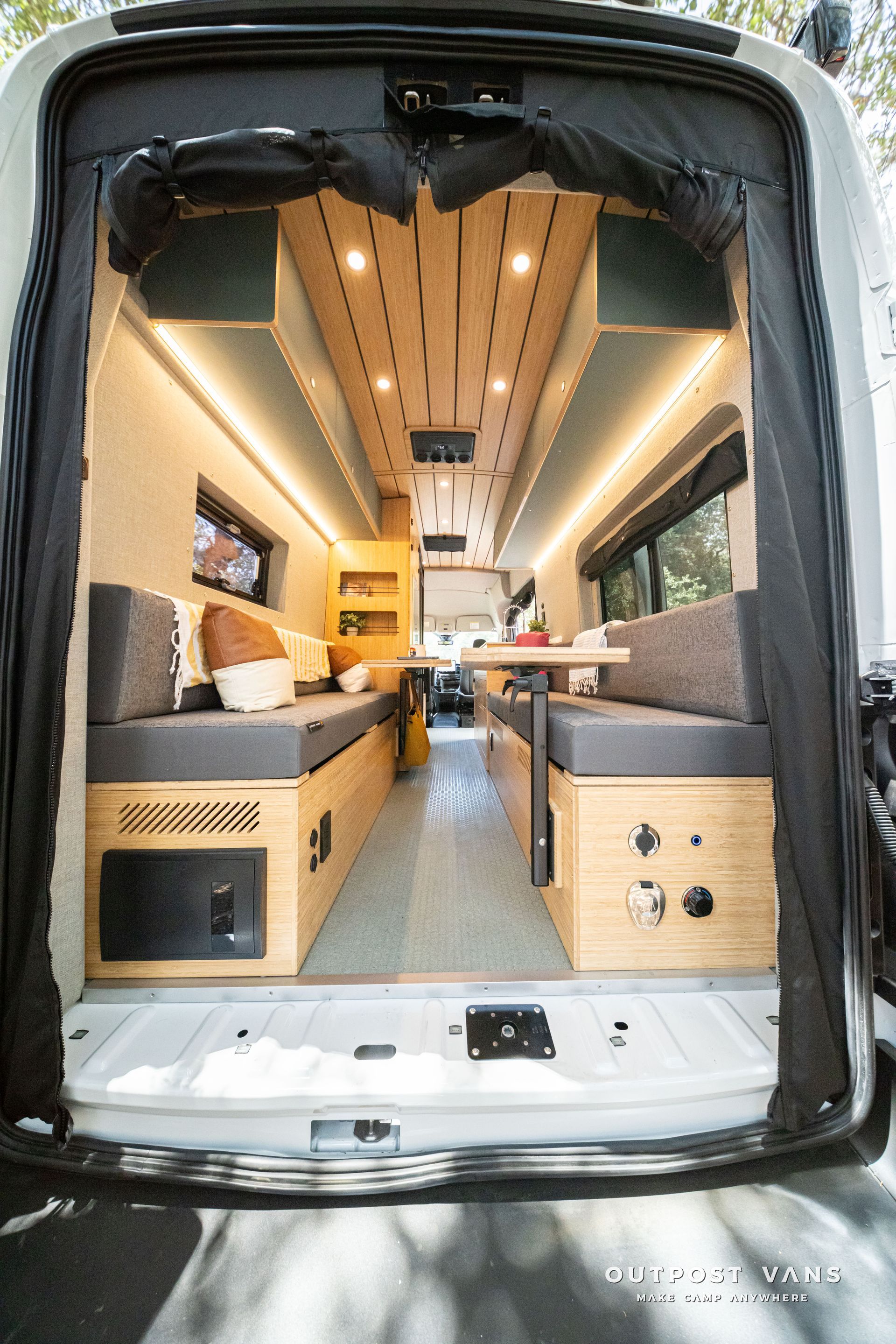Van interior converted to a cozy camper with wood ceiling, side benches, and aisle lighting