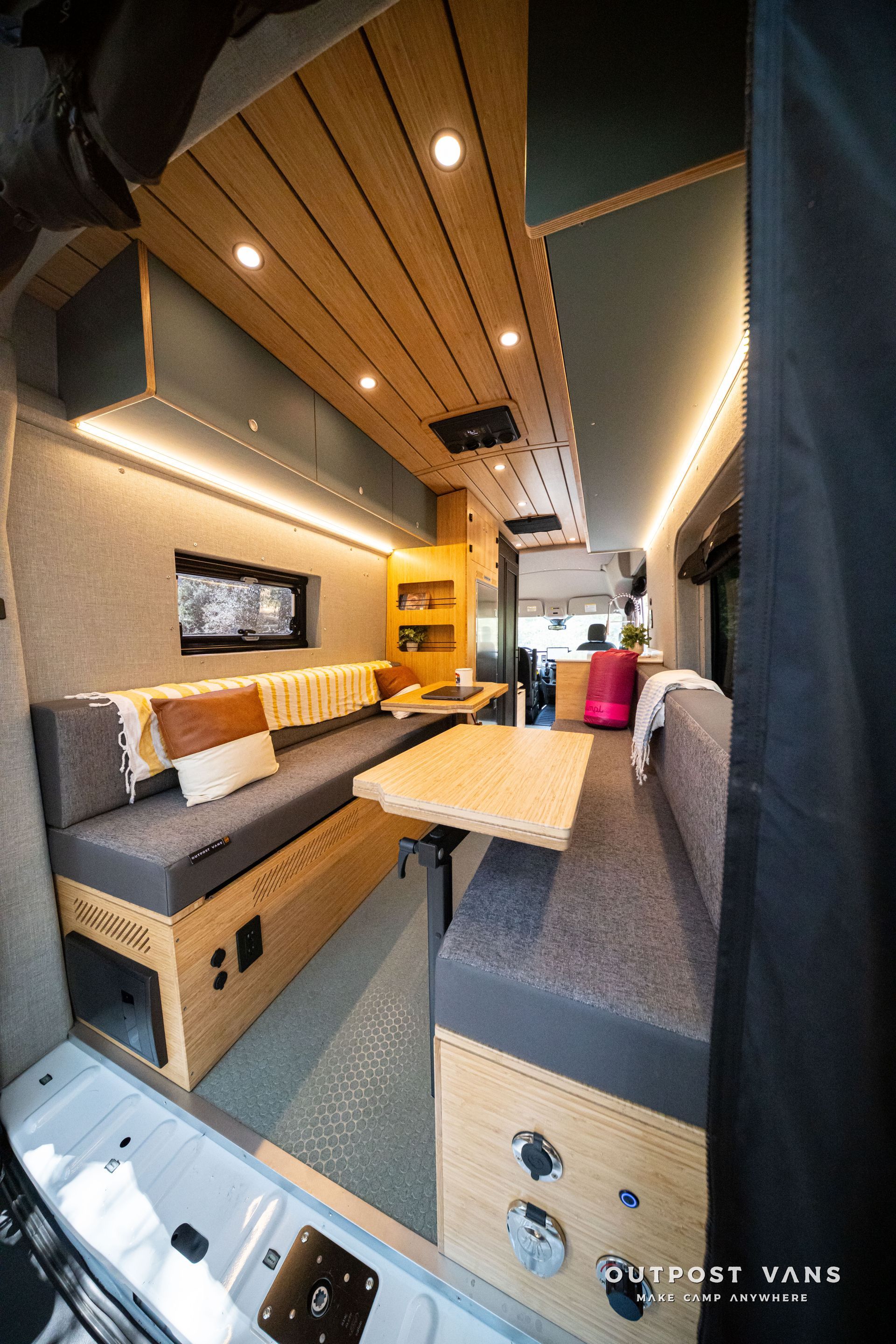 Modern camper van interior with wooden ceiling, bench seating, and a small table