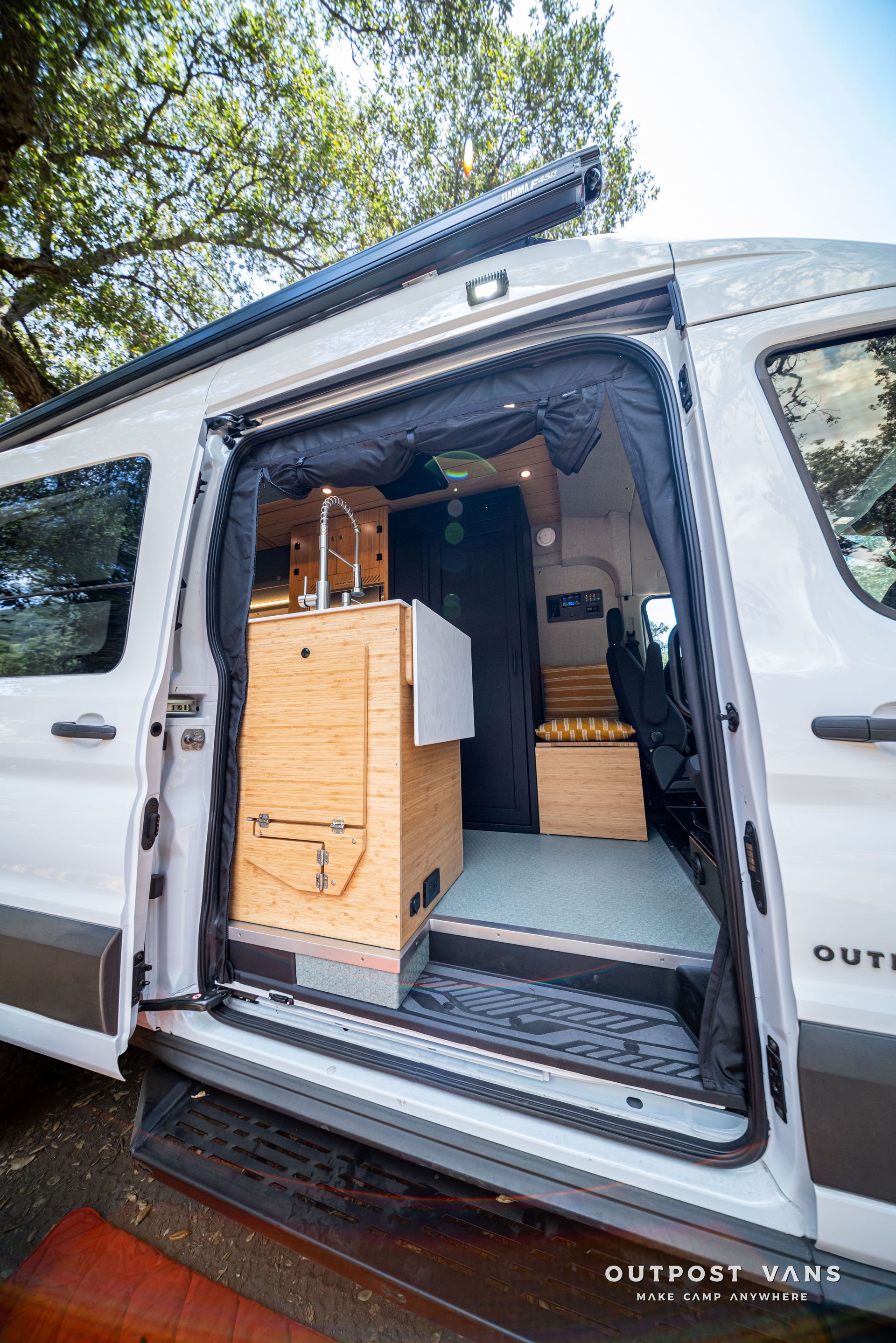 Open van with side door open, showing built-in storage drawers and a sleeping setup inside.