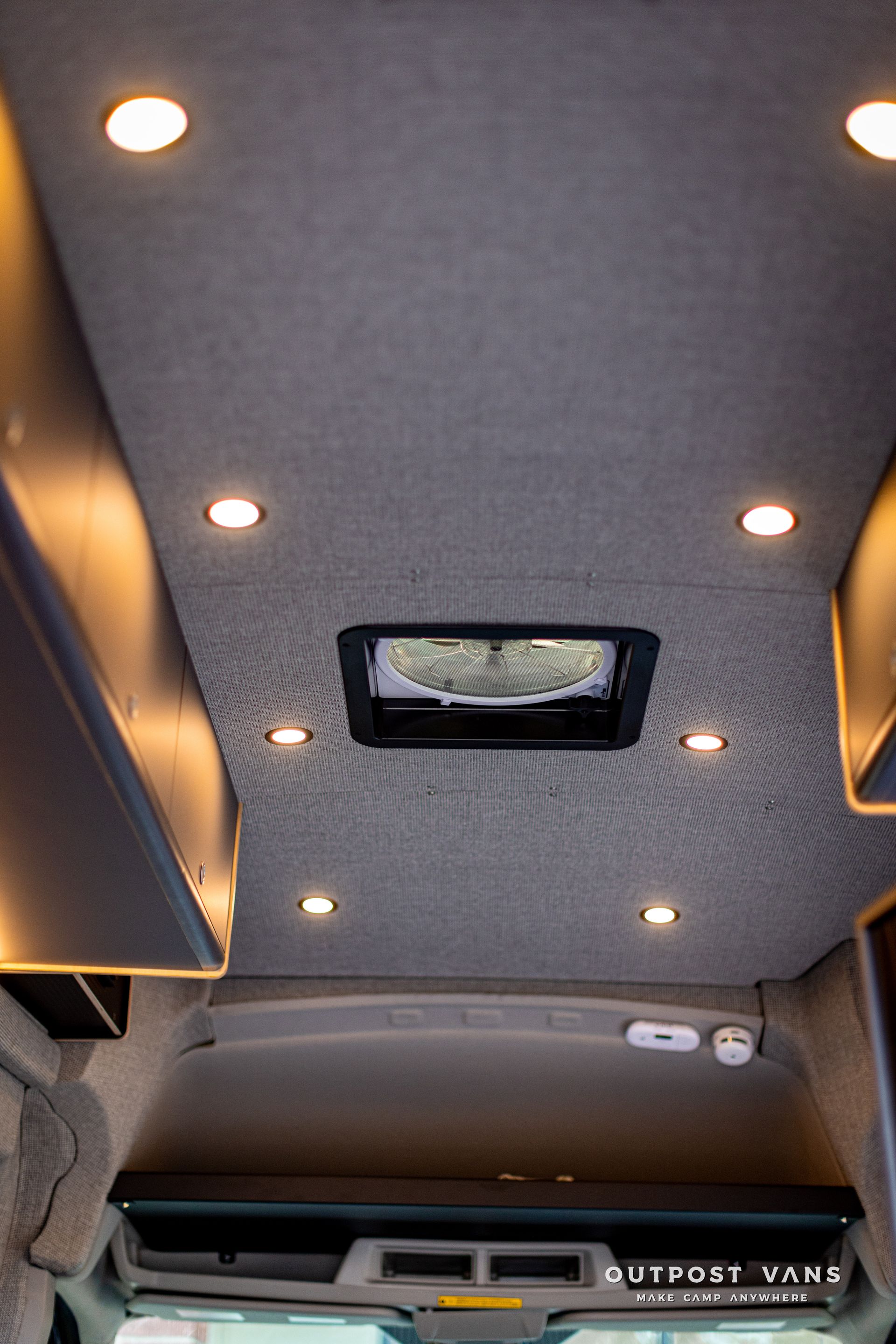 the ceiling of a van with a fan and lights on it .