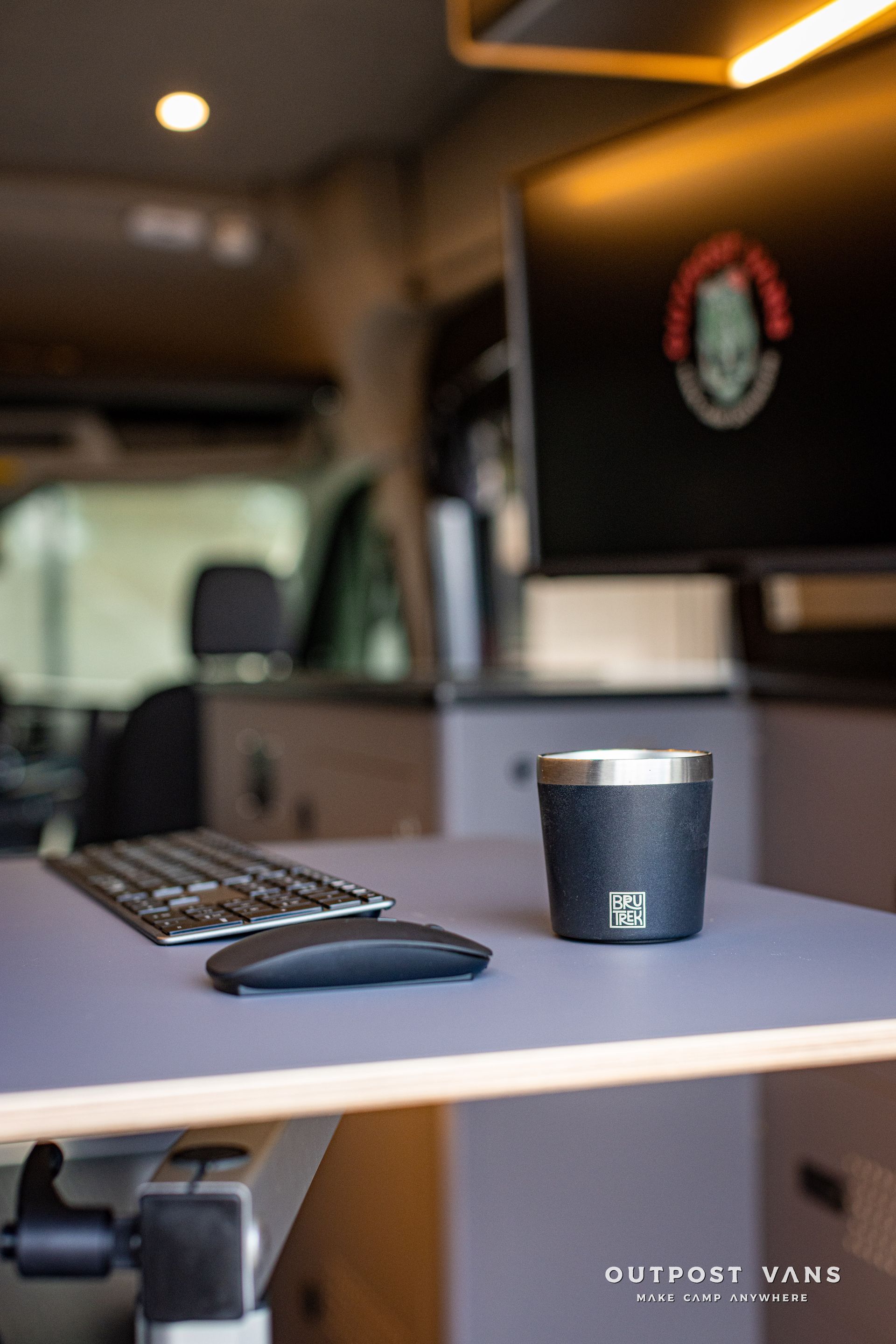 a desk with a keyboard , mouse and cup on it .