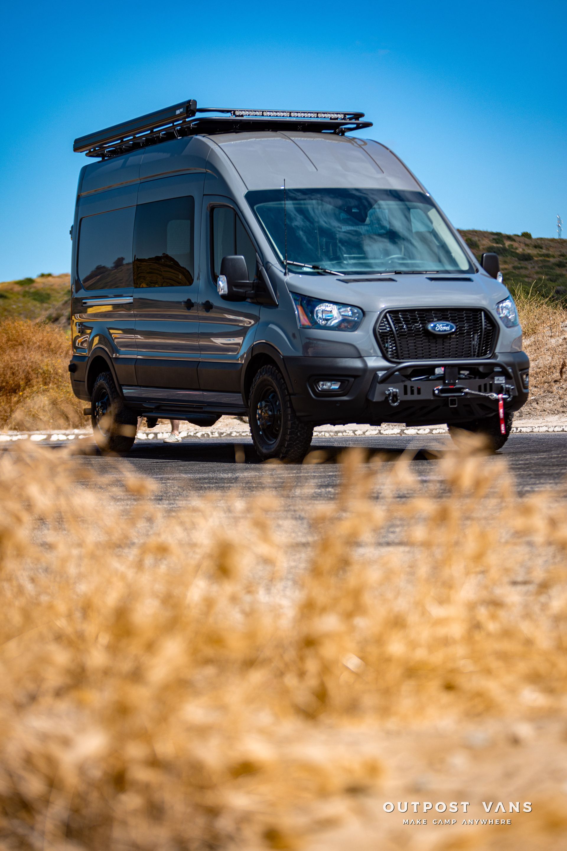 a ford transit van is parked on the side of the road .