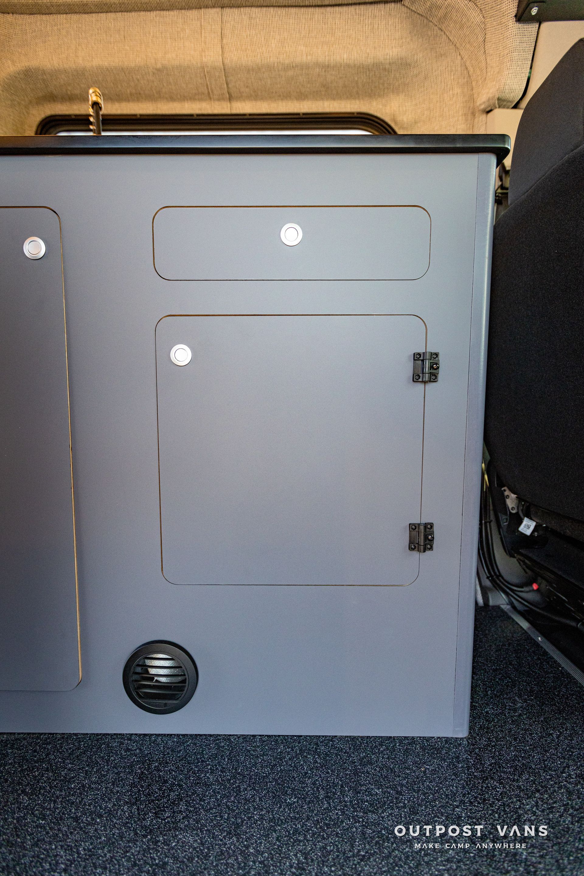 a gray cabinet is sitting on the floor next to a black chair .