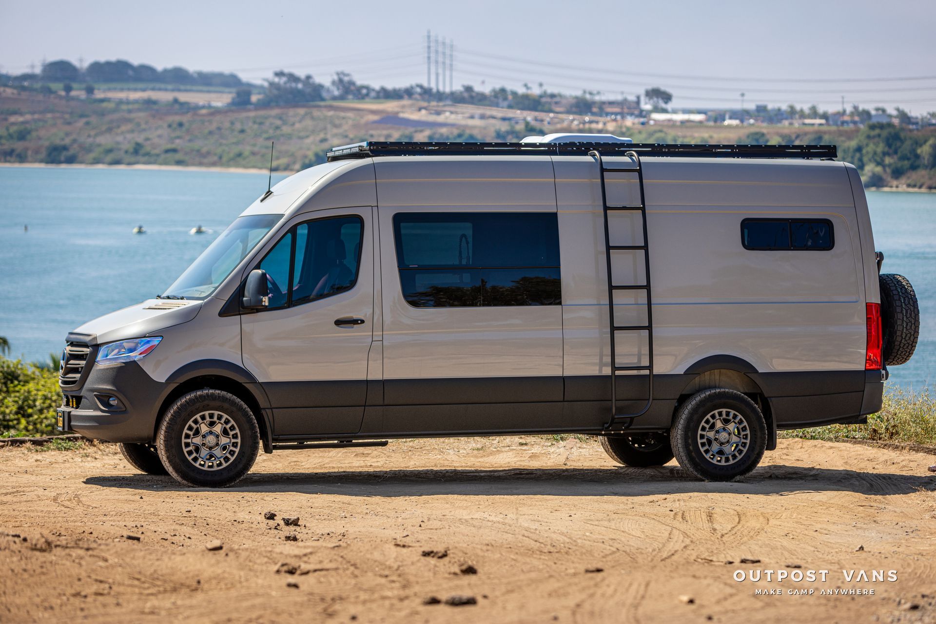 A van is parked on top of a dirt hill next to a body of water.