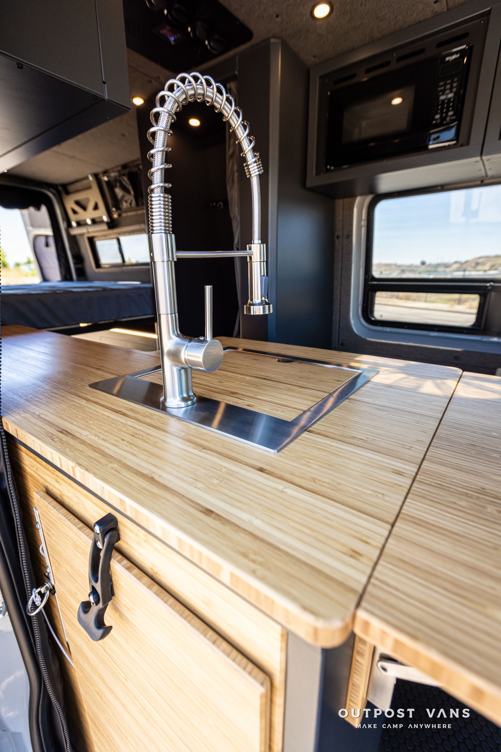 A kitchen in a van with a sink and a microwave.