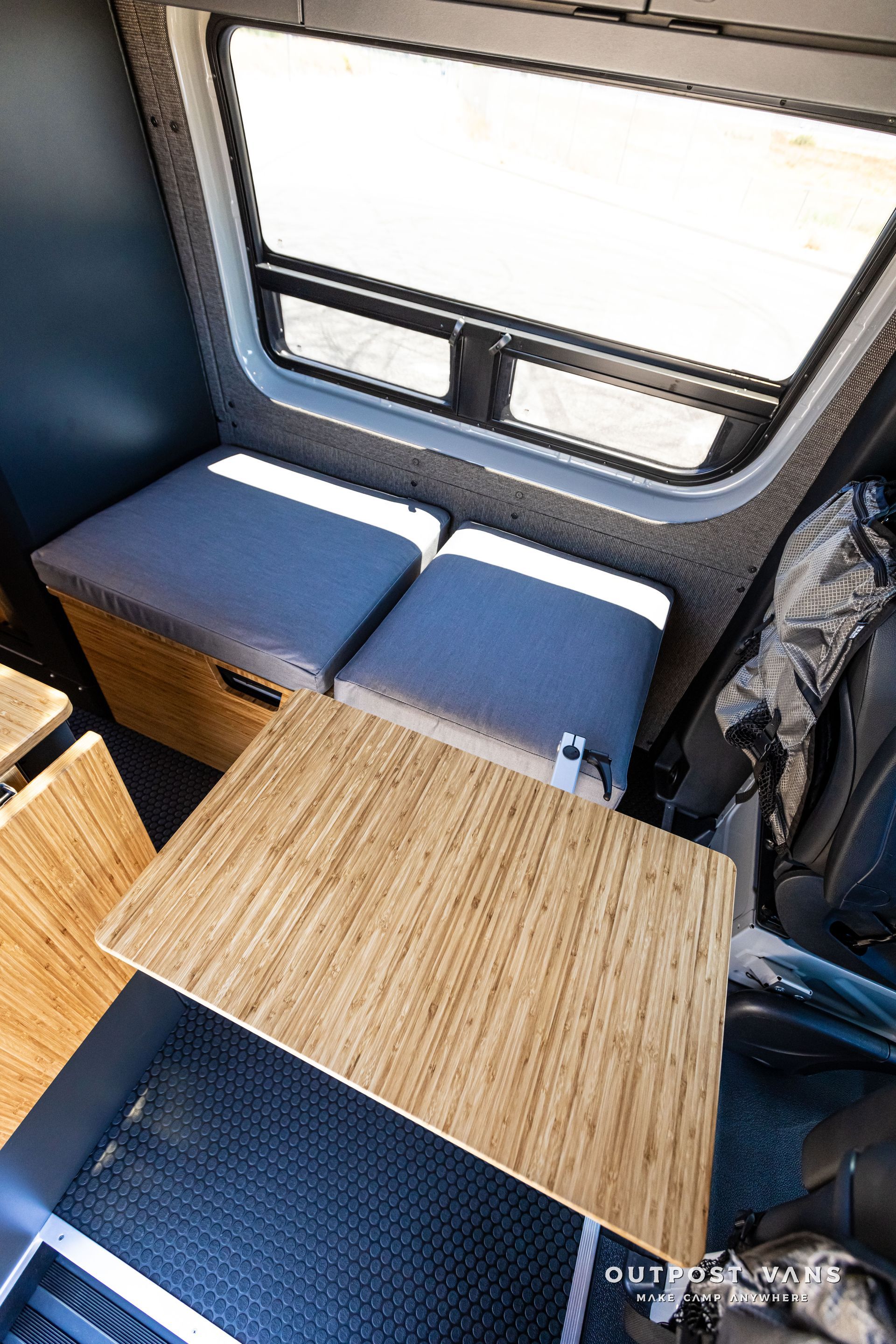 A wooden table is sitting in the back of a van next to a window.