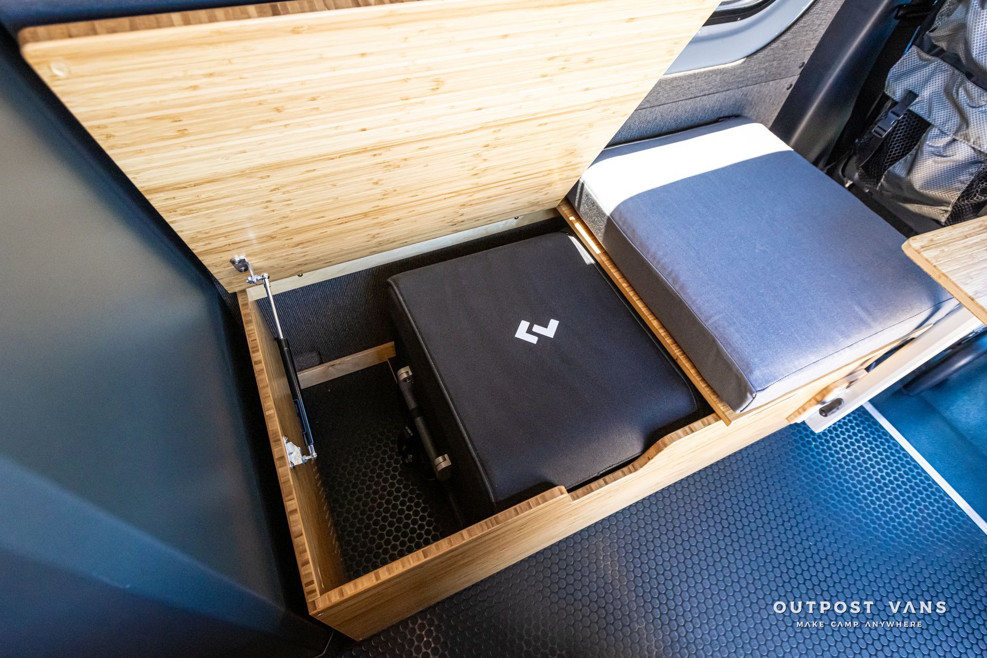 A laptop is sitting in a wooden box in the back of a van.