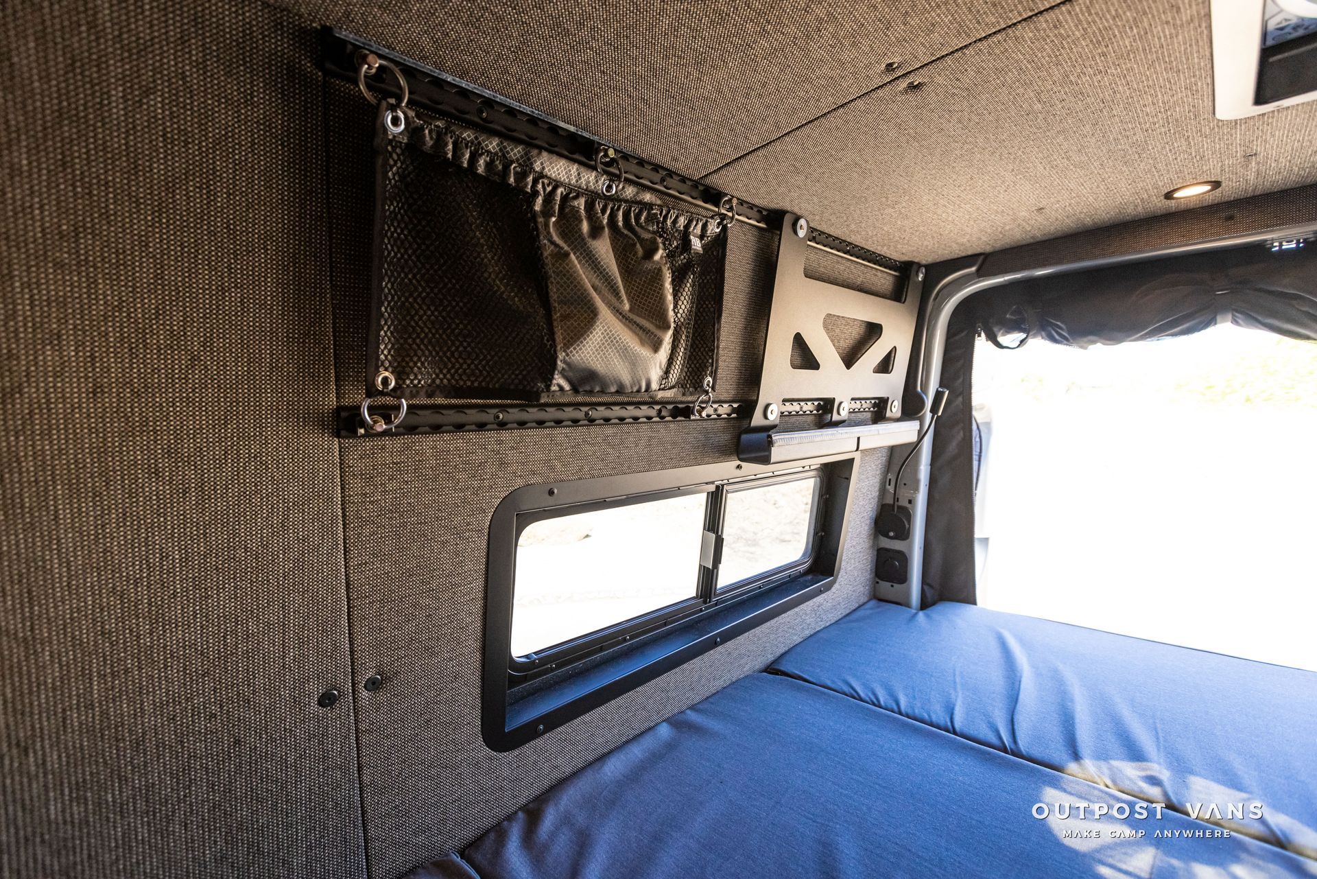 The inside of a van with a bed and a window.