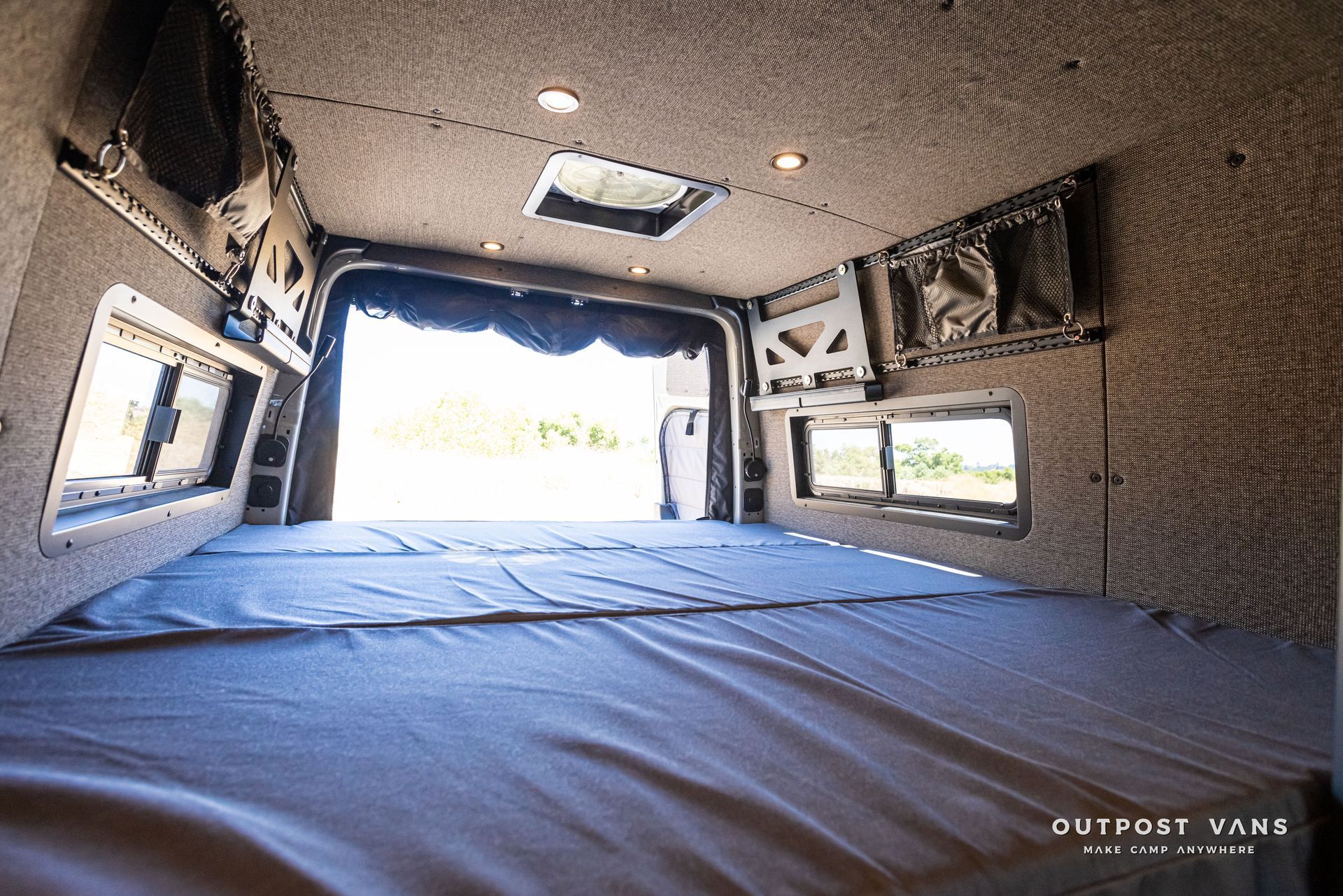 The inside of a van with a bed and a window.