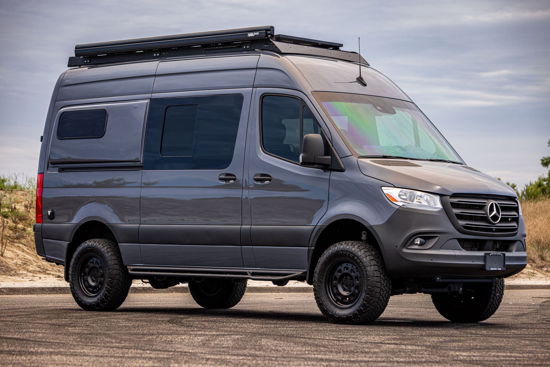 A mercedes benz sprinter van is parked on the side of the road.