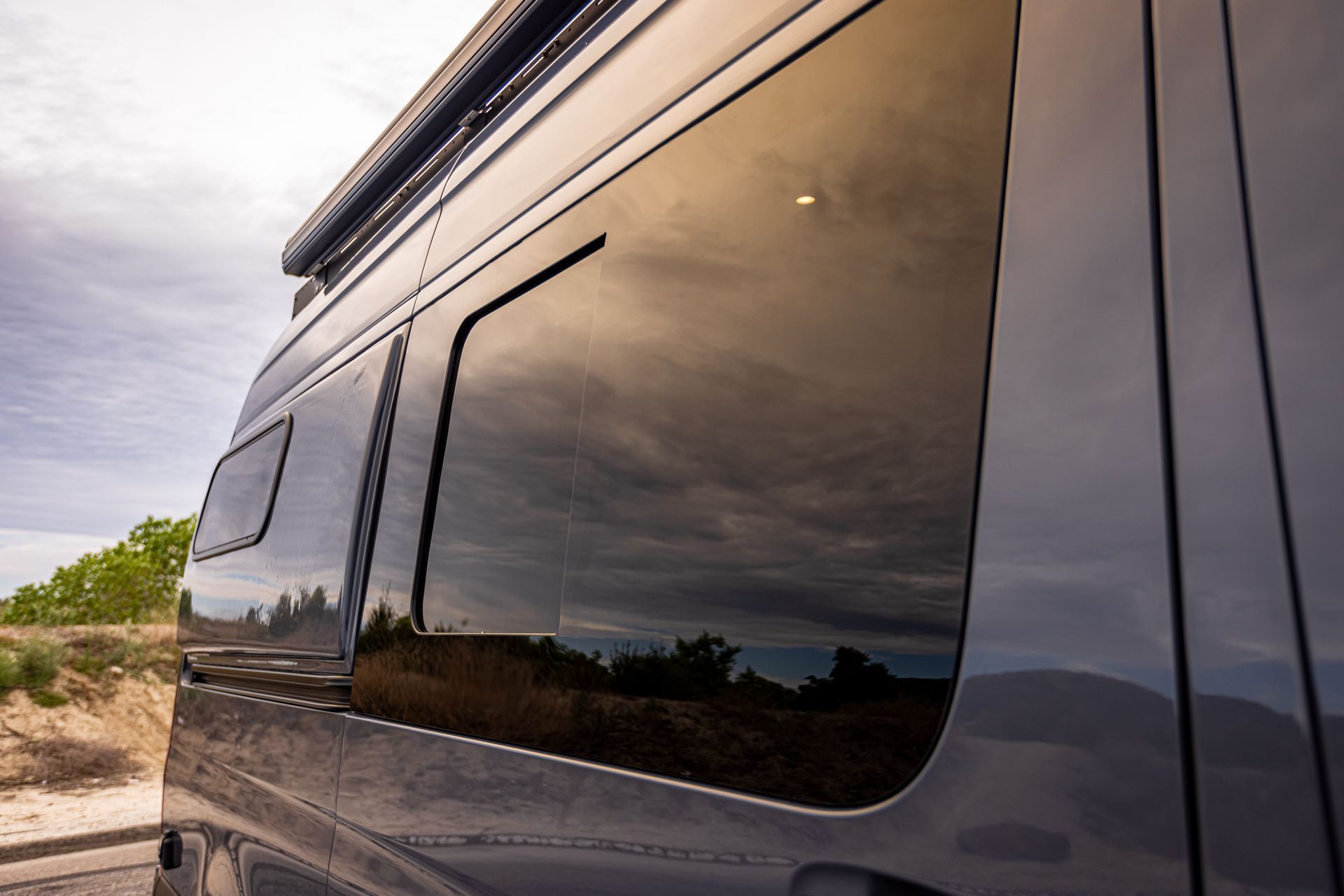 A black van with a large window is parked on the side of the road.