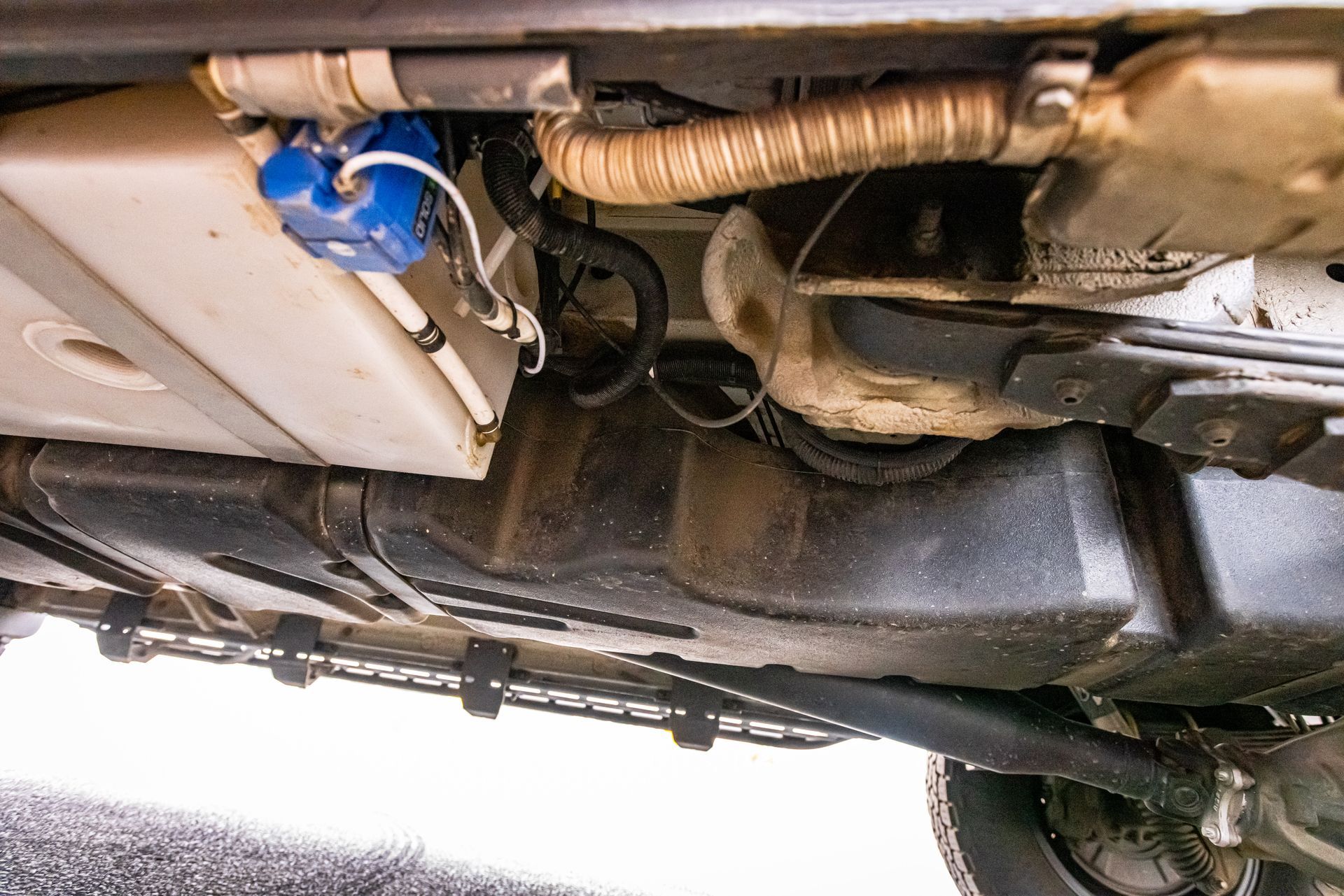 A close up of the underside of a car with a fuel tank