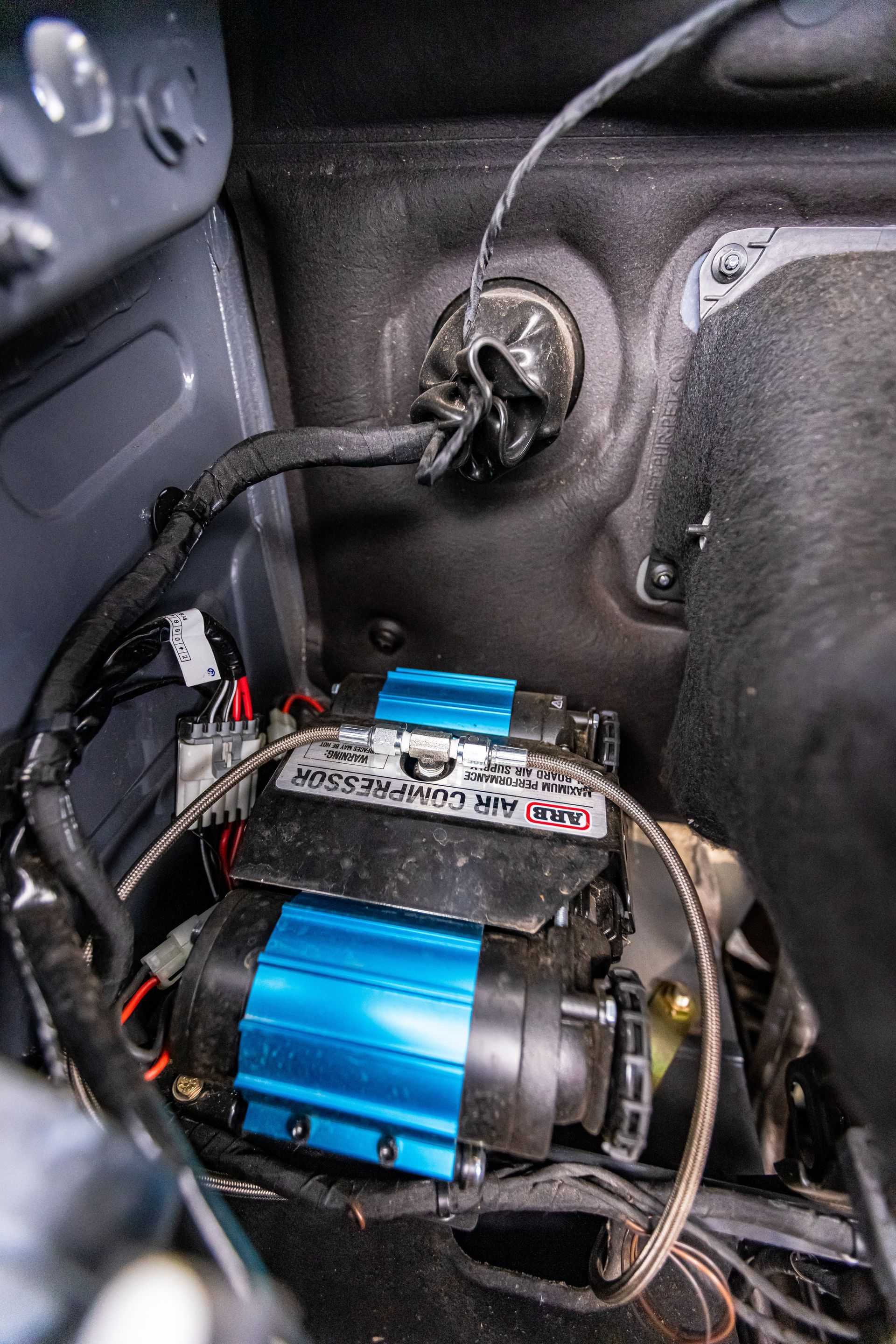 A blue air compressor is sitting inside of a car.