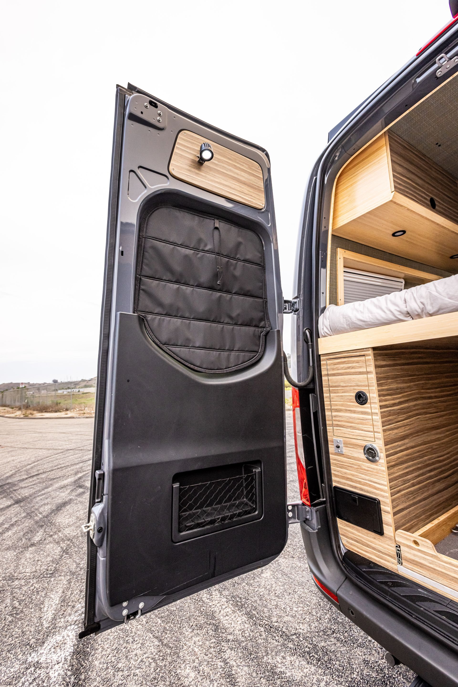A van with the door open and a bed in the back.