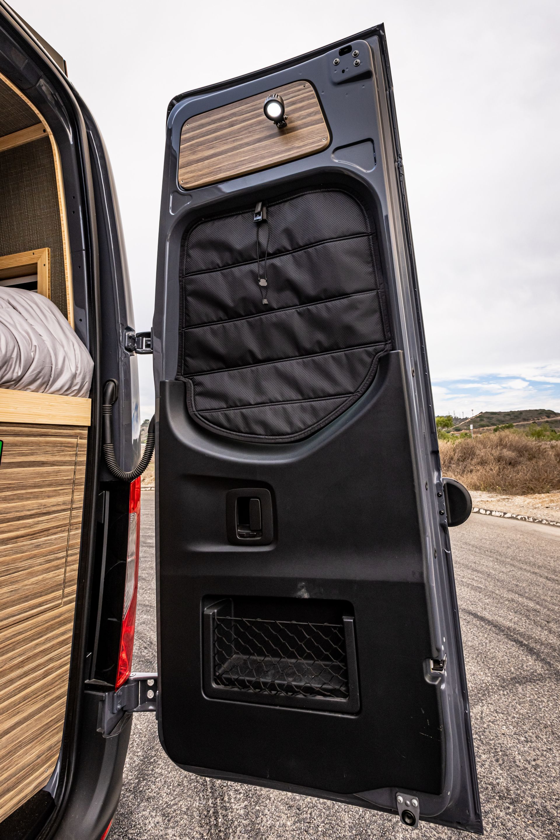 A black van with the door open is parked on the side of the road.