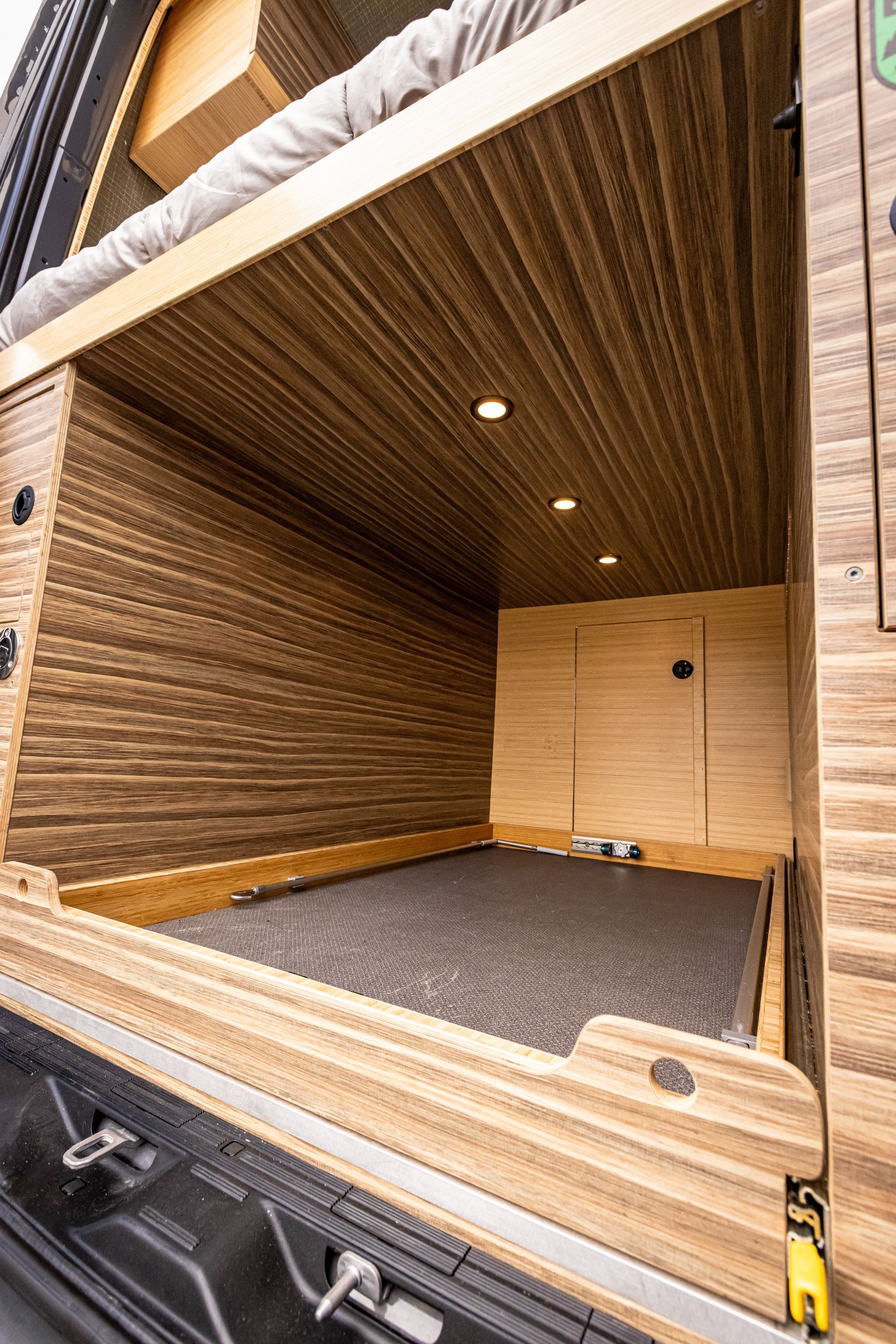 The inside of a wooden van with a bed in the back.