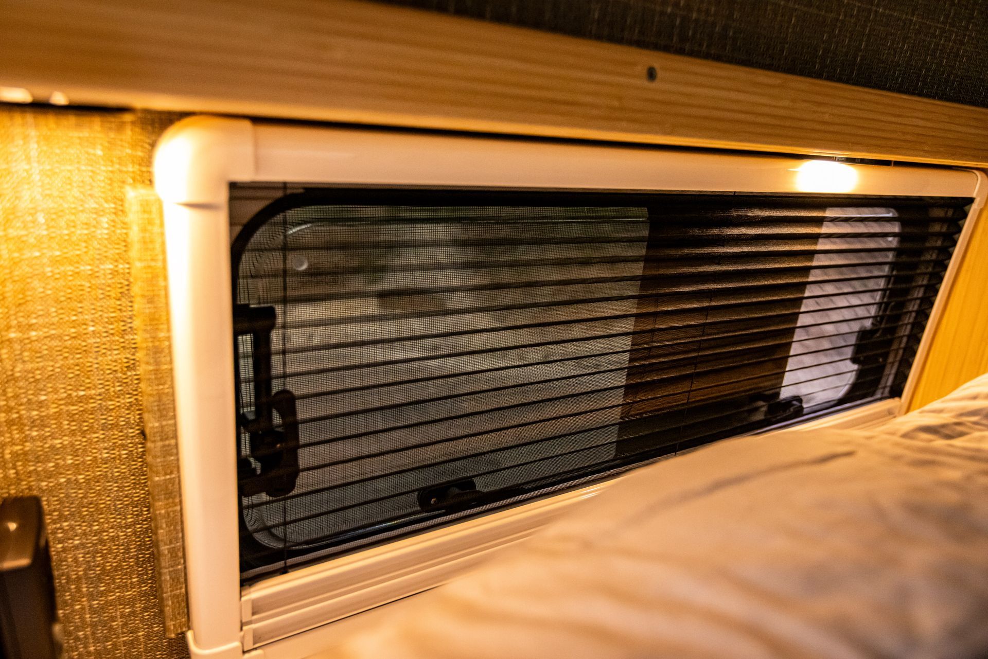 A close up of a window with blinds in a camper van.
