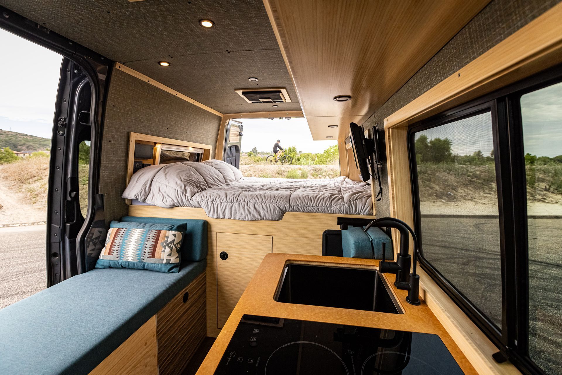The inside of a van with a bed and a kitchen.