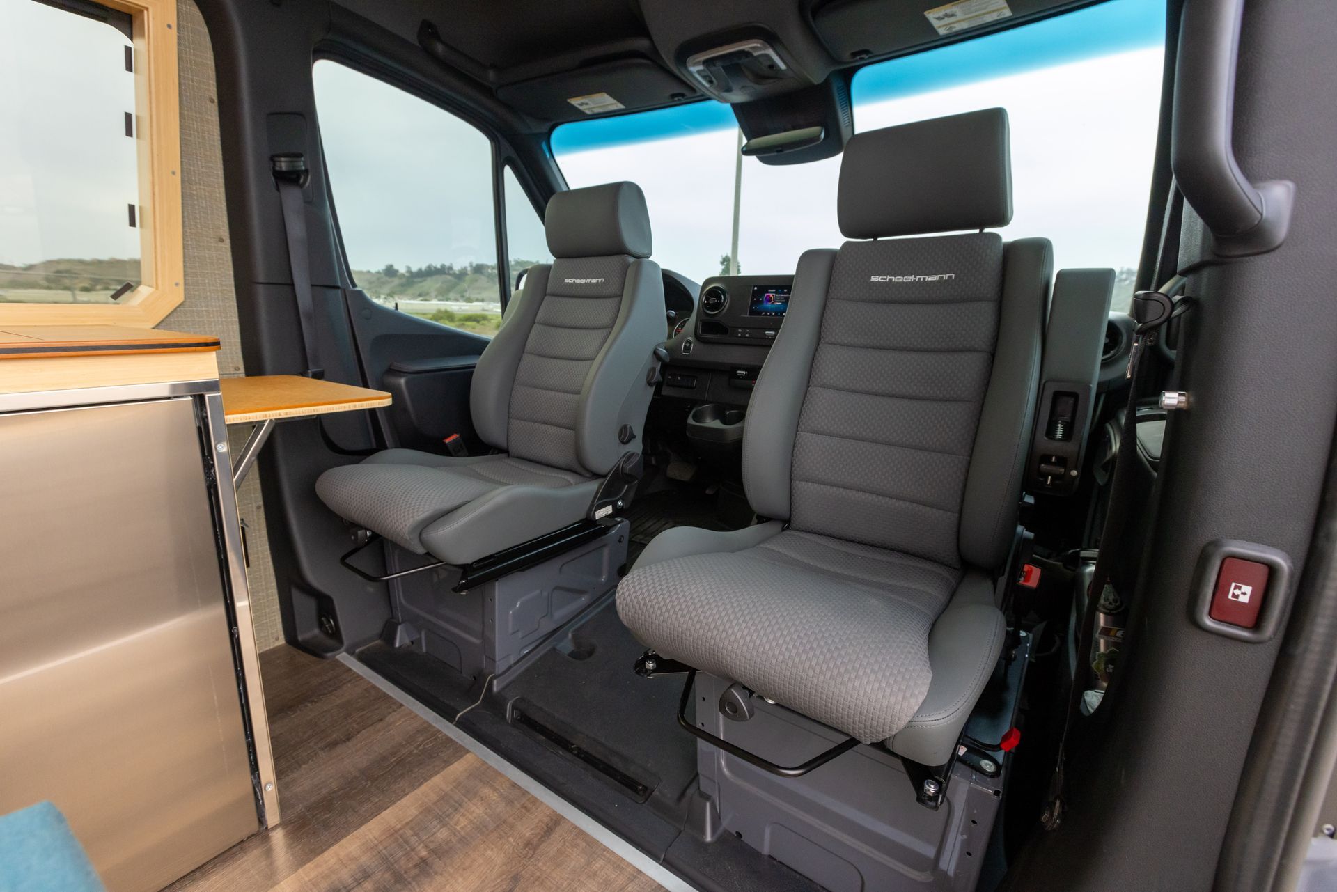 The interior of a van with two seats and a table.