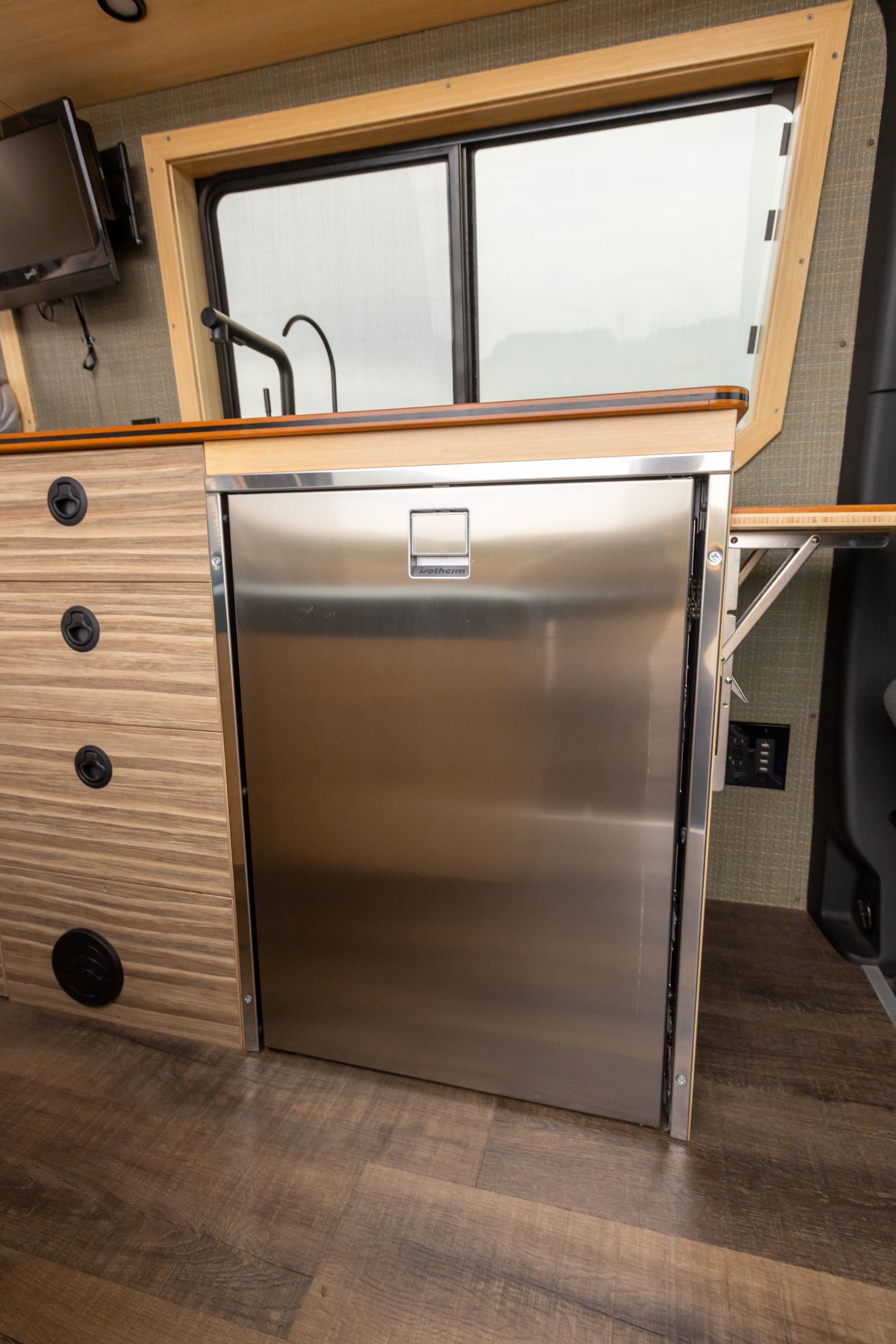A stainless steel refrigerator is sitting in a kitchen next to a window.