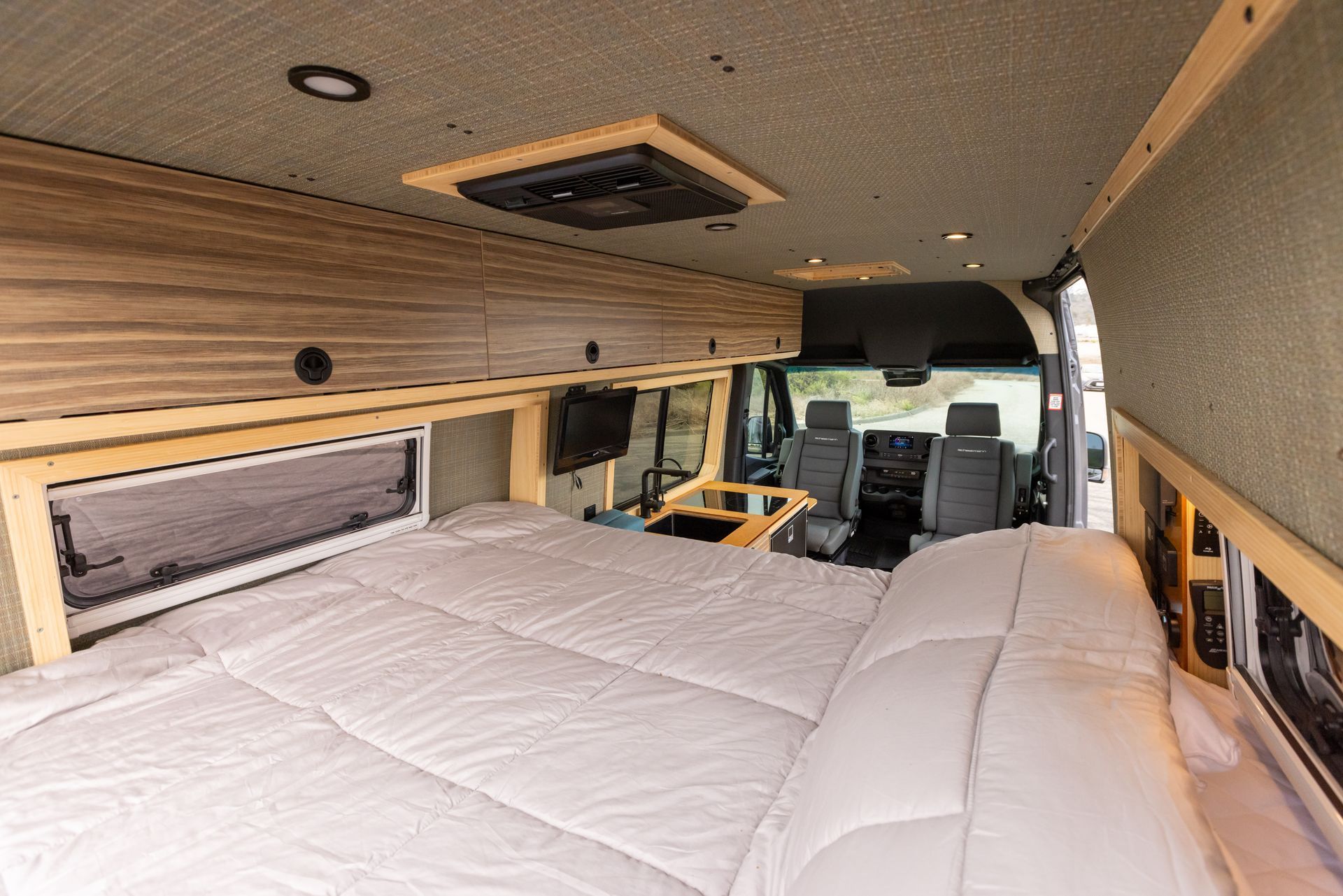 The inside of a van with a bed and a table.