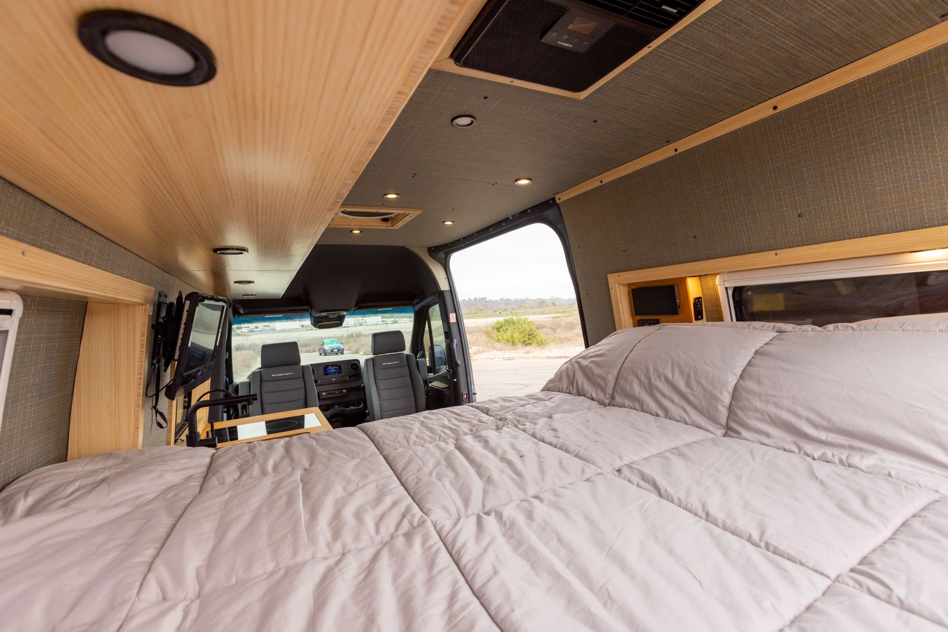 The inside of a van with a bed and a ceiling fan.