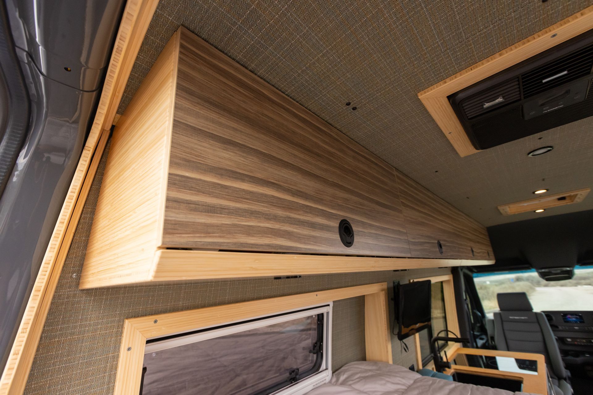The inside of a van with a bed and a ceiling fan.