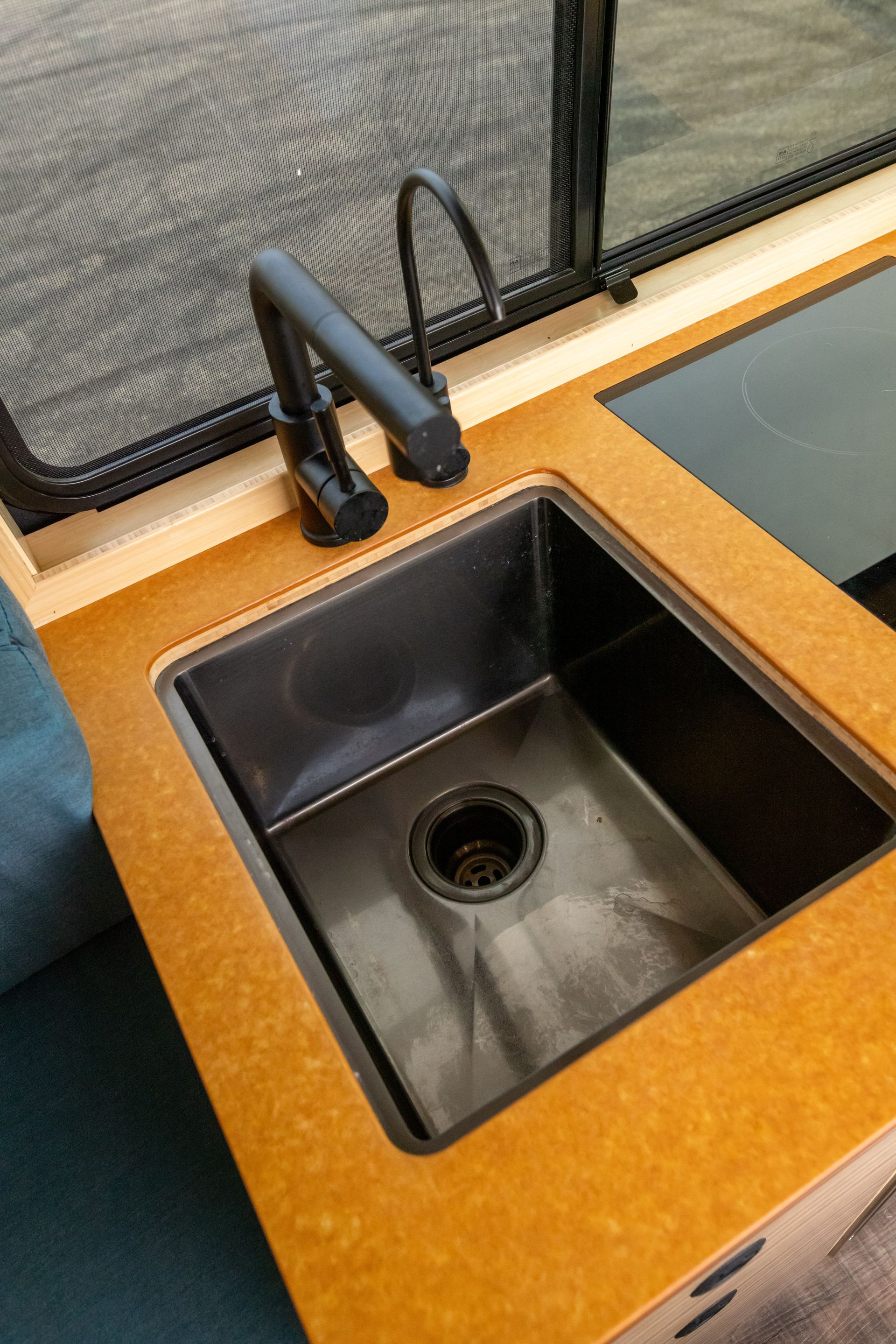 A stainless steel sink with a black faucet on a wooden counter top.