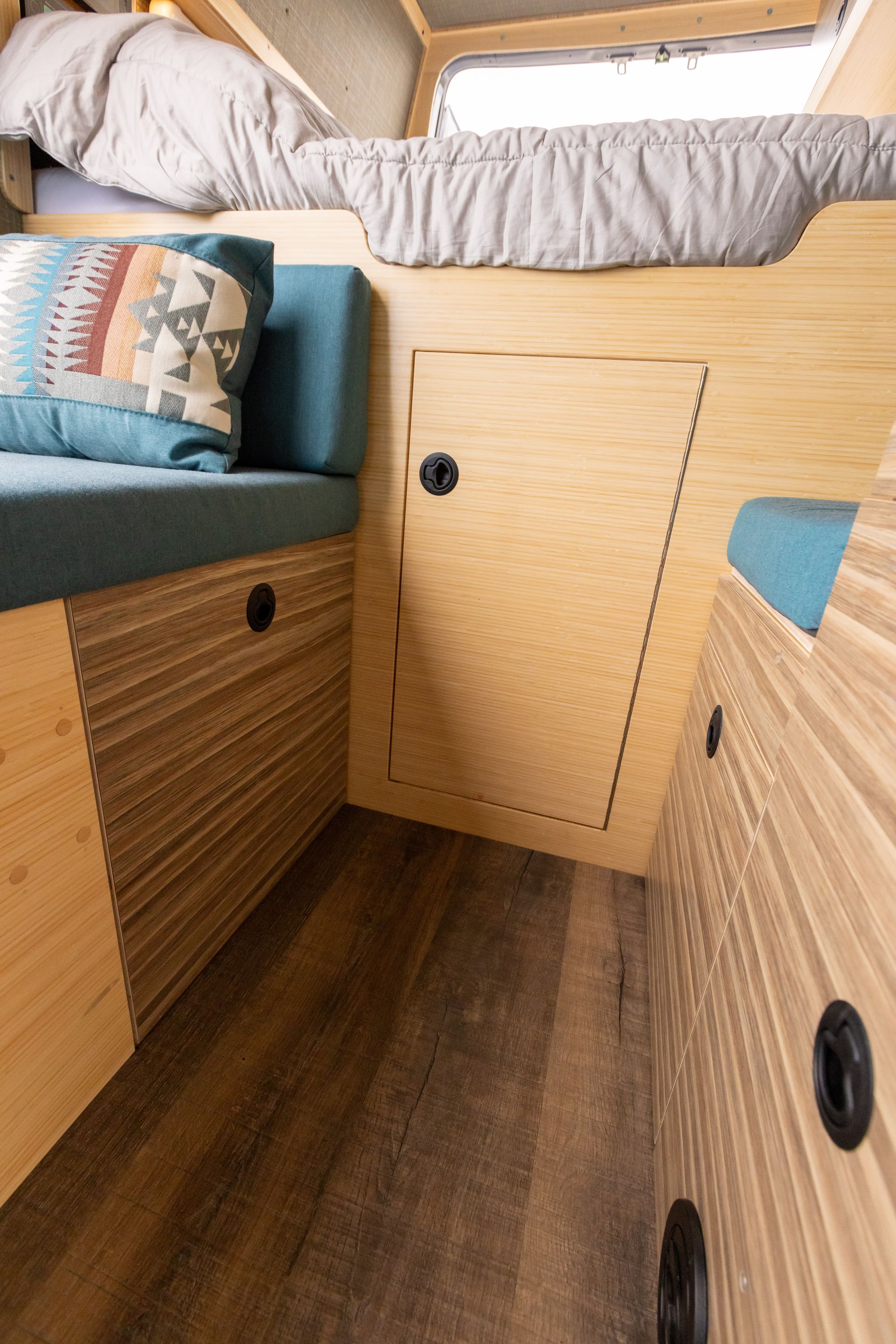 A bedroom in a camper with a bed and a couch.