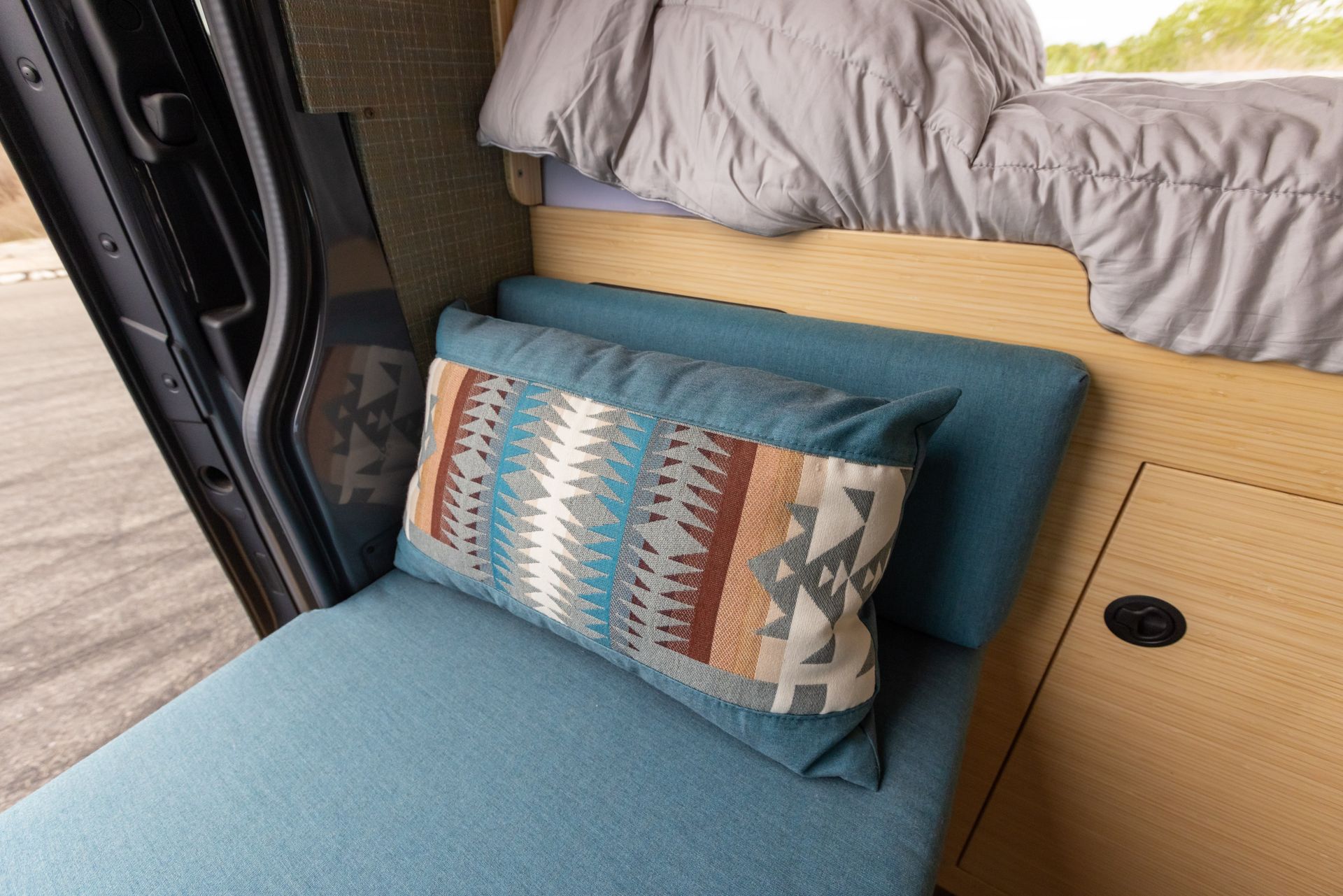 A blue couch with a pillow on it in a van.