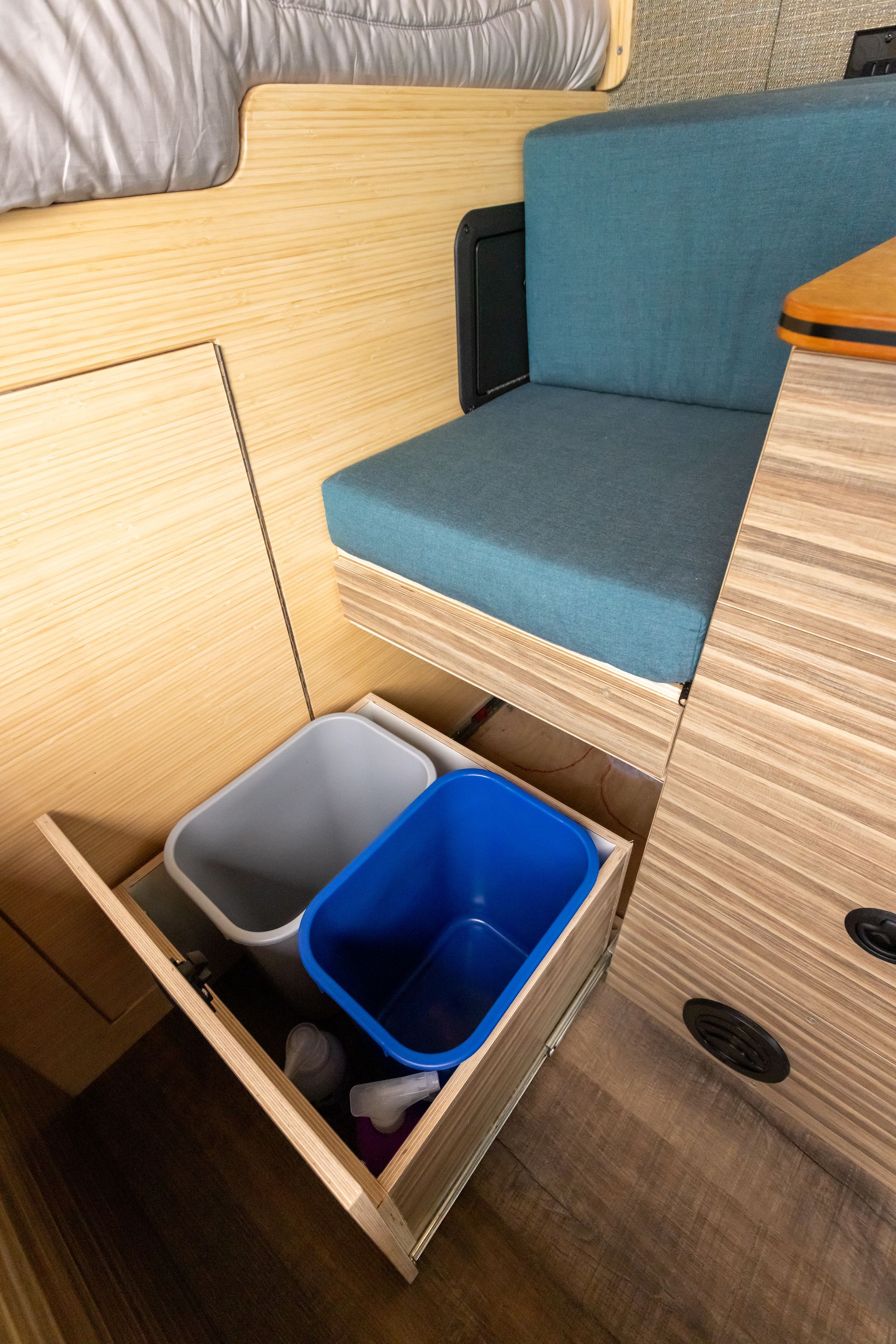 A wooden drawer with two trash cans in it
