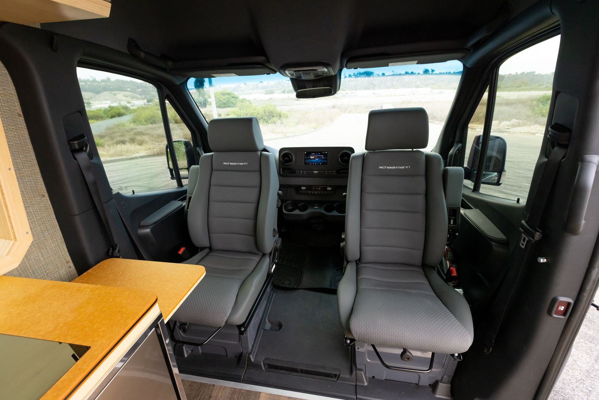 The interior of a van with two seats and a table.