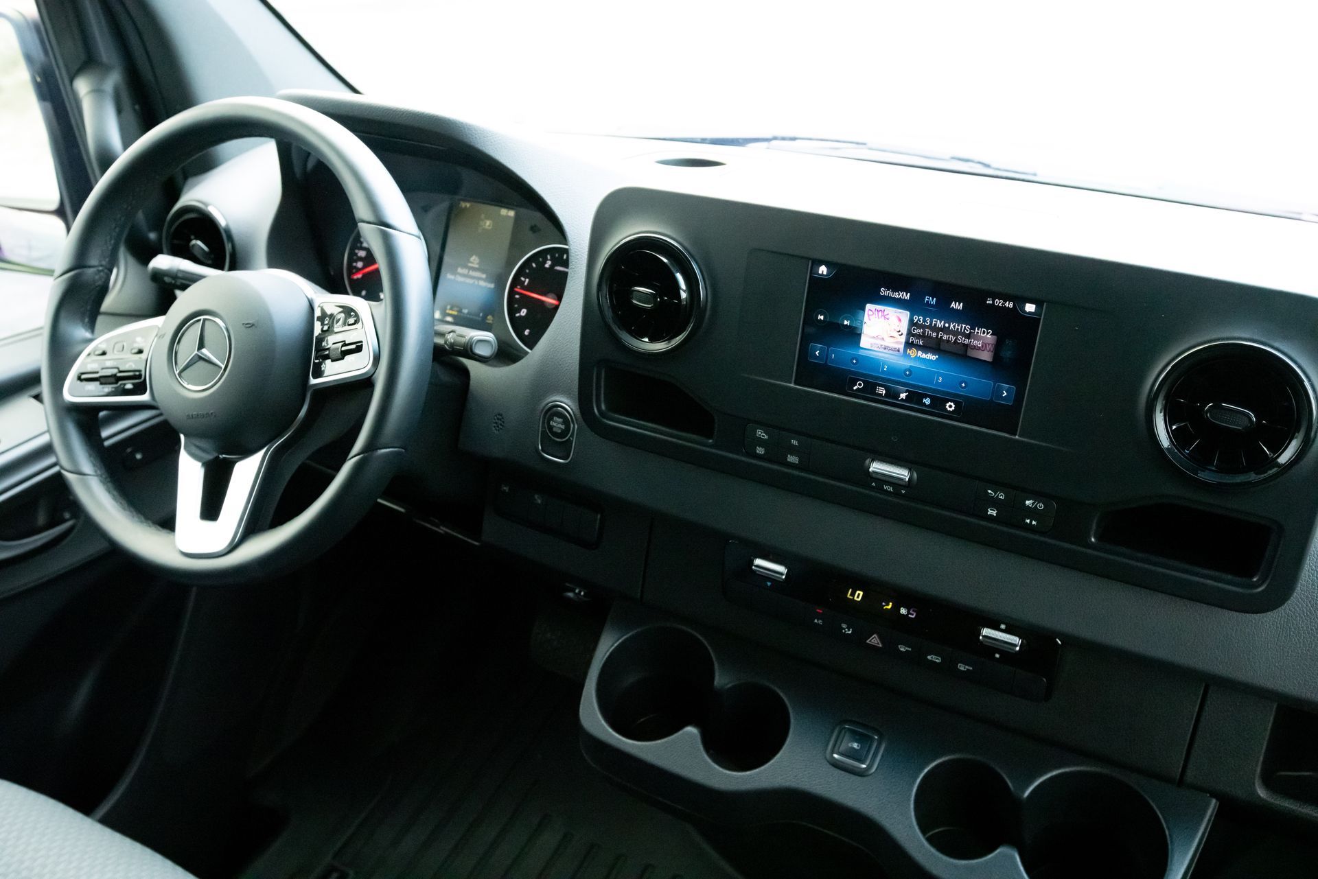 The interior of a mercedes sprinter van with a steering wheel and dashboard.