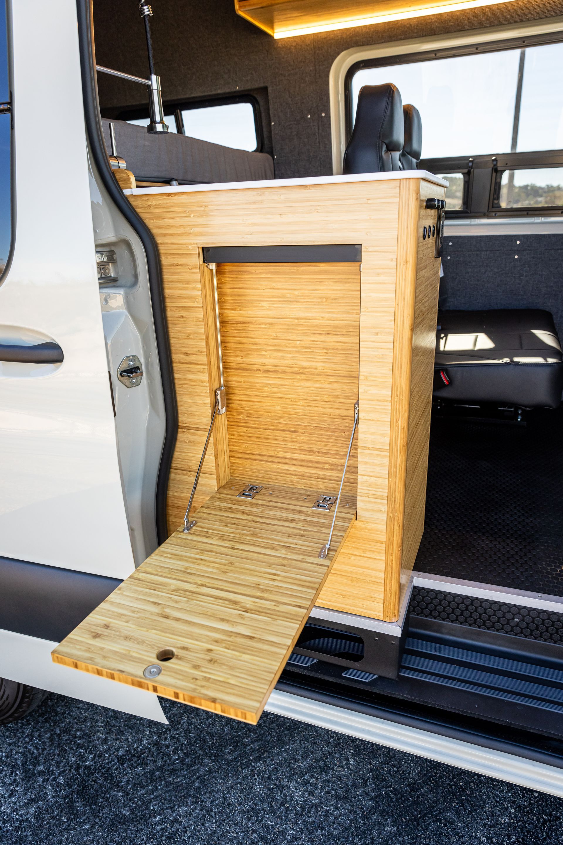 A van with the door open and a wooden table in the back.