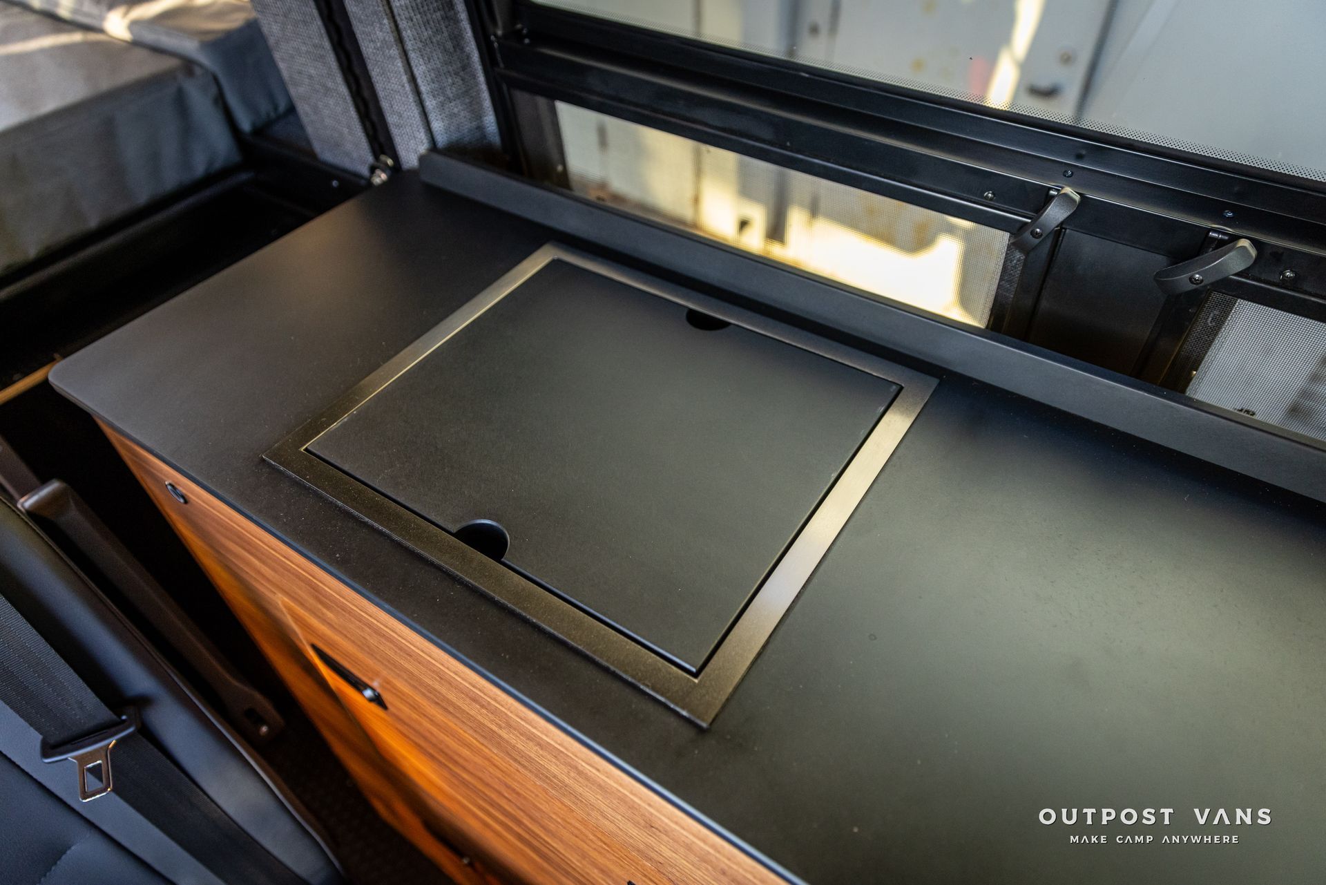 a black counter top with a drawer underneath it and a window .