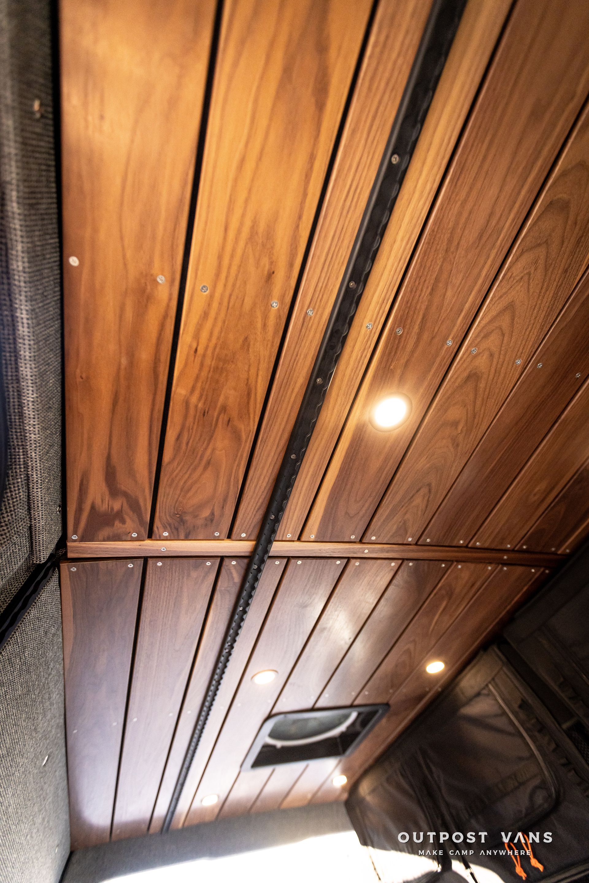 the ceiling of a van is made of wood and has lights on it .