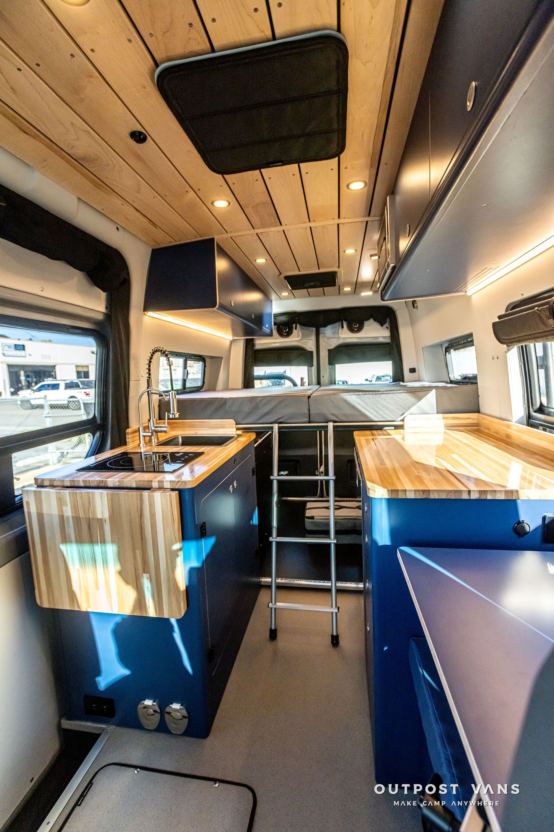 The inside of a van with a kitchen and a bed.