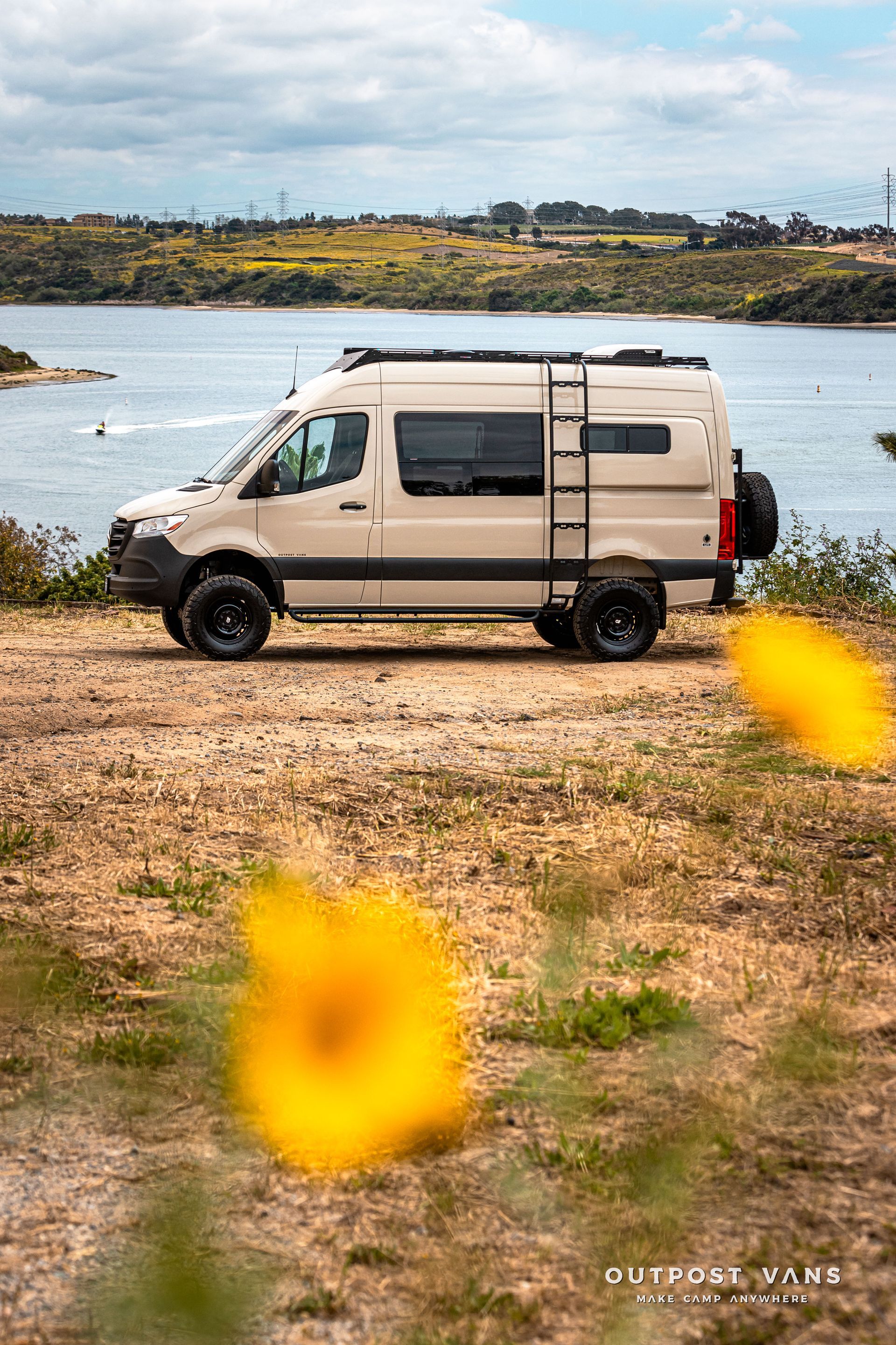 A white van is parked in a field next to a body of water.