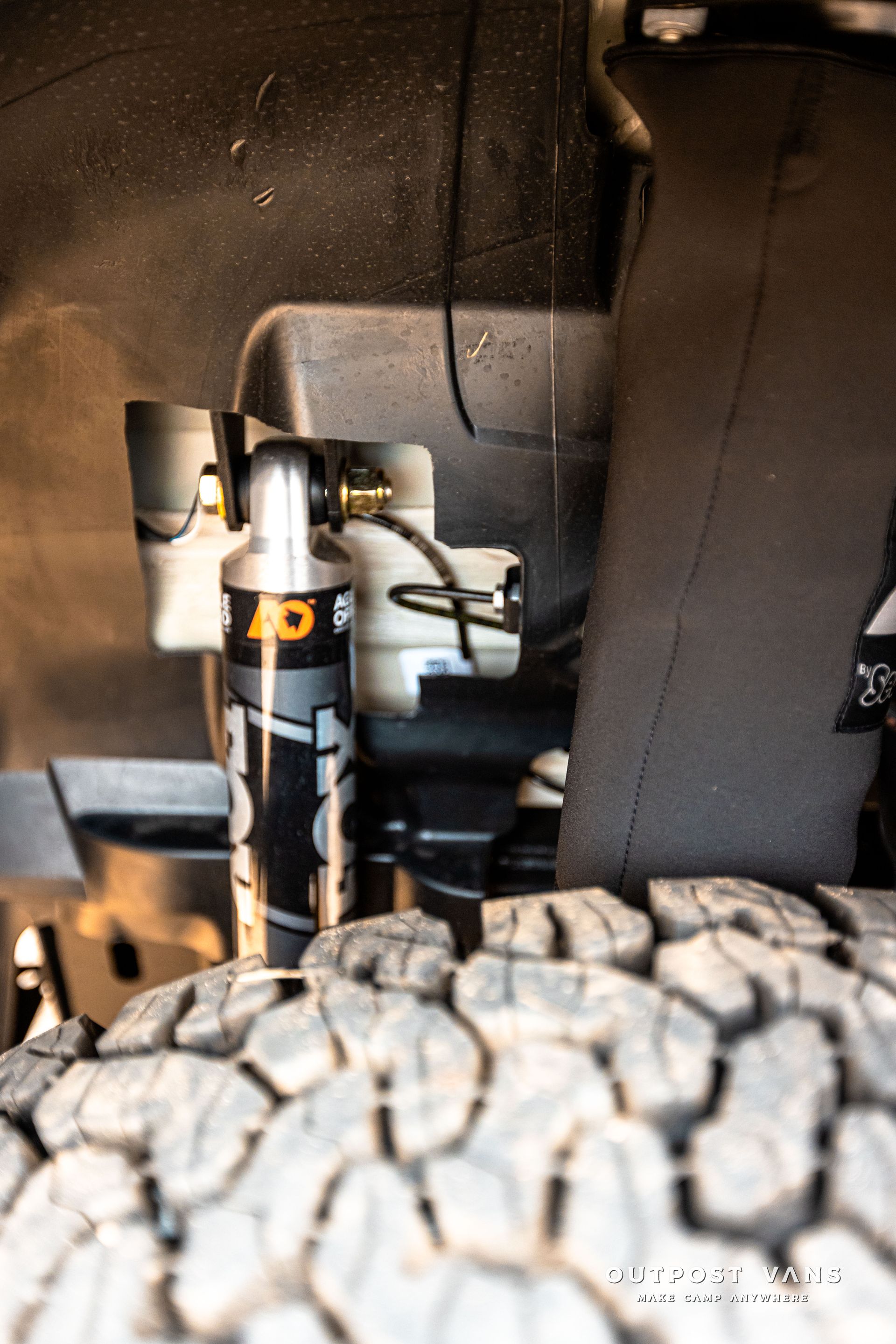 A close up of a shock absorber and a tire on a truck.