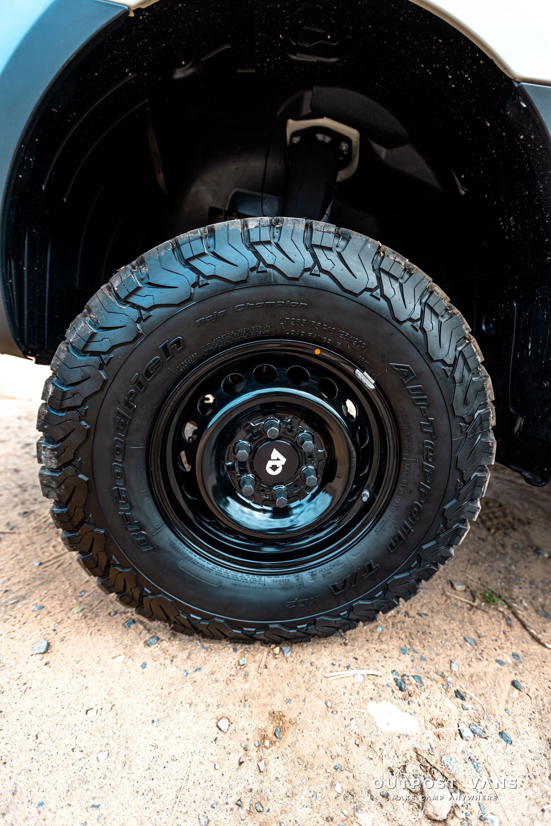 A close up of a tire on a car on a dirt road.