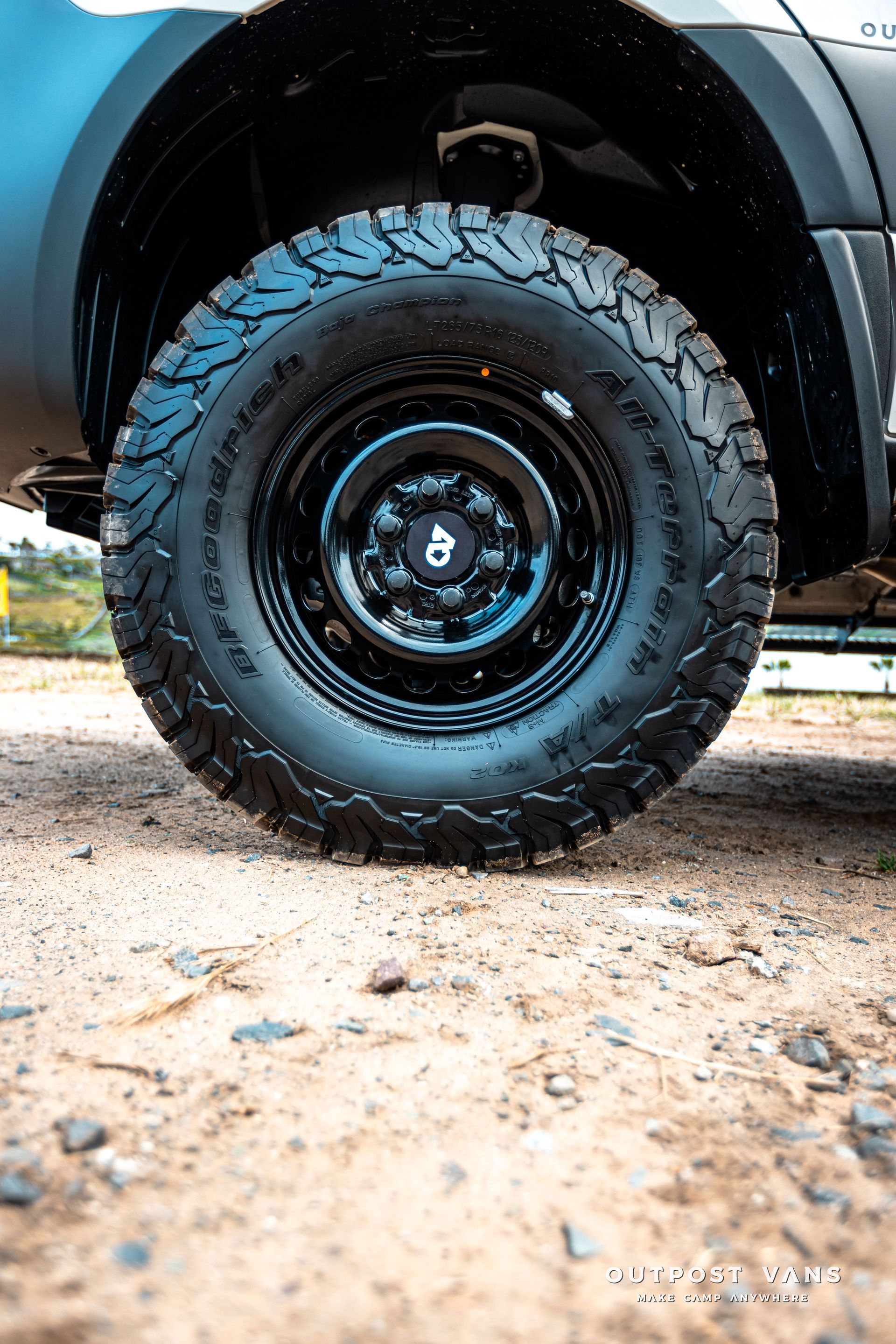 A close up of a tire on a truck on a dirt road.