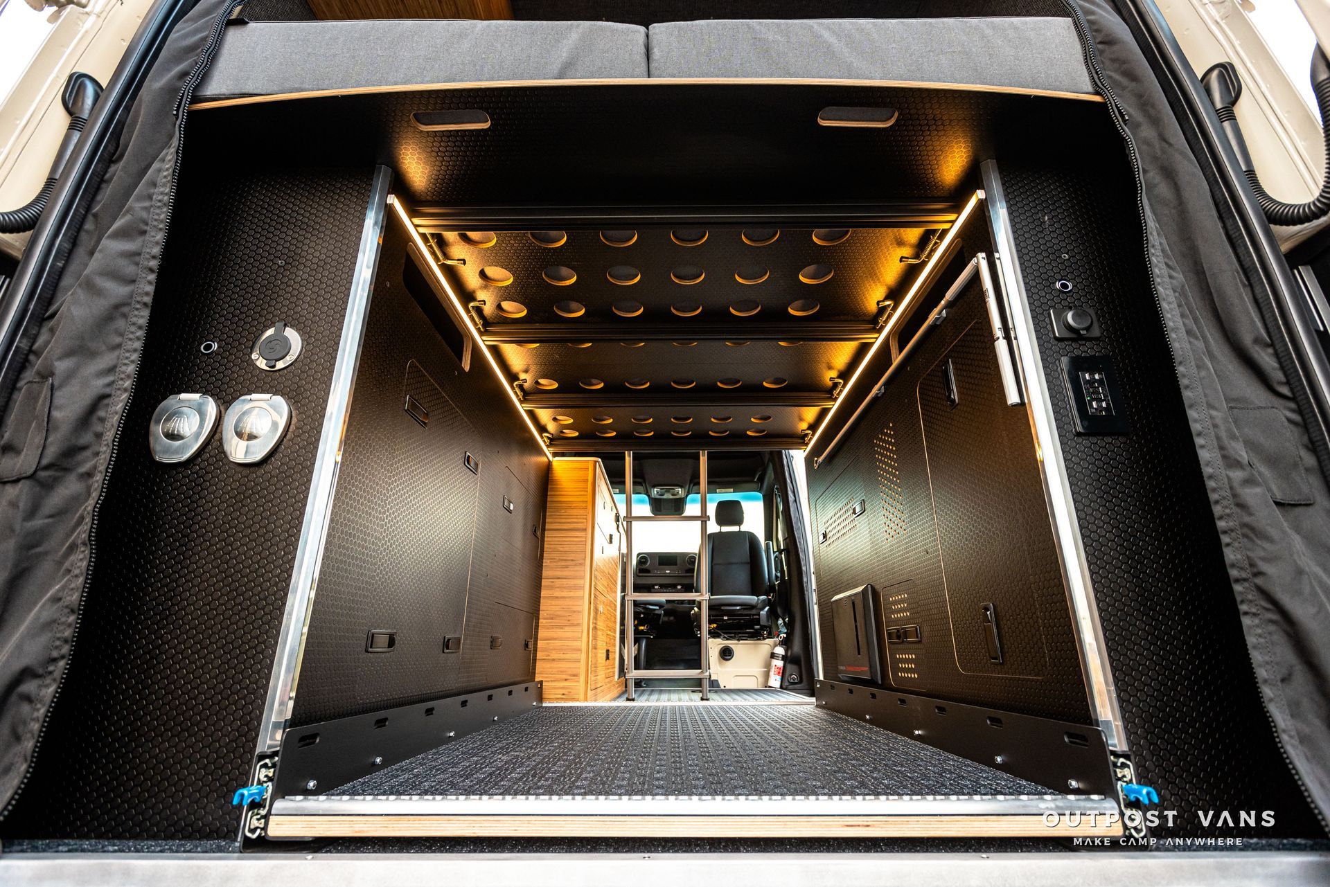 The trunk of a truck is open and has a ladder in it.