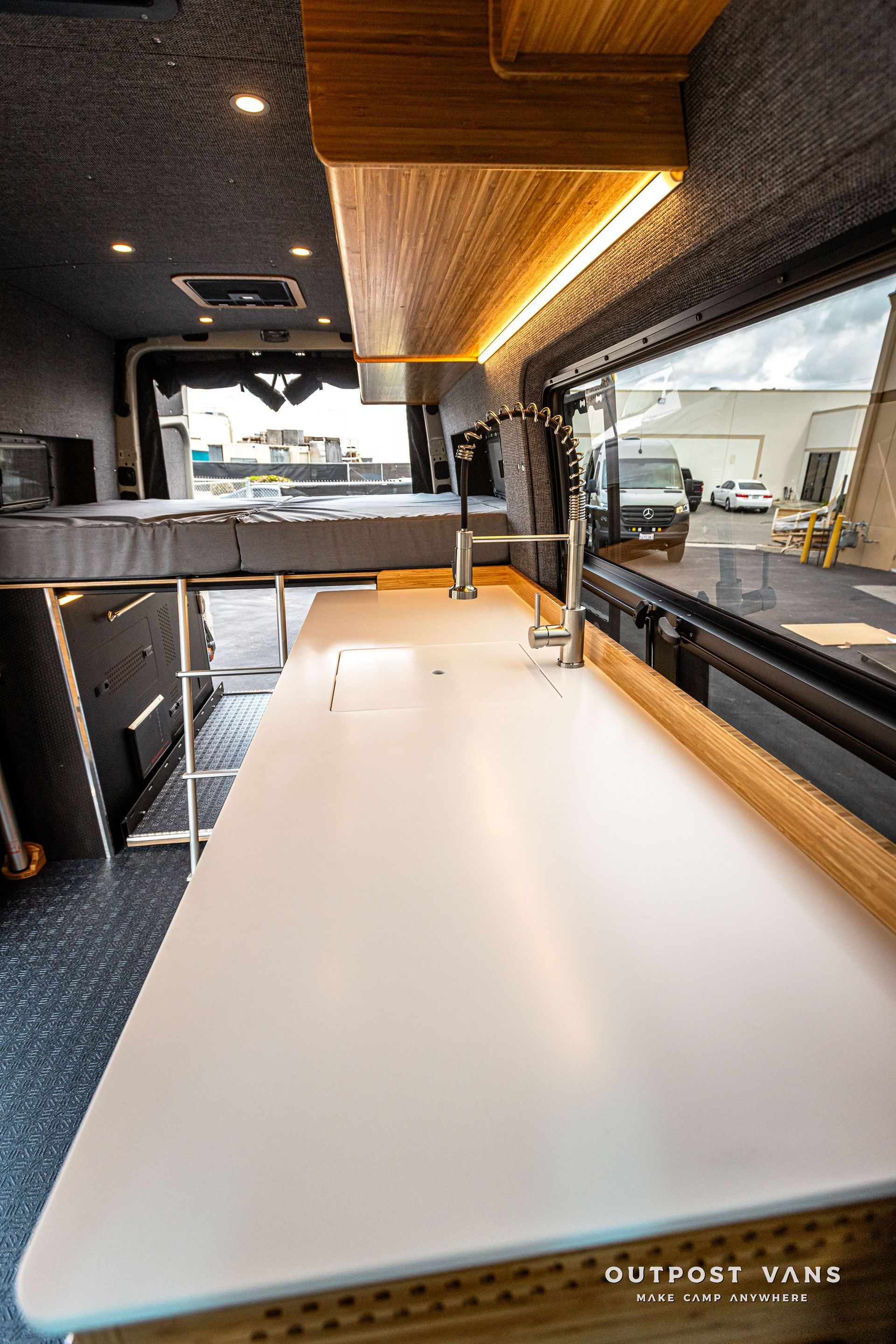 A kitchen in a van with a white counter top and a sink.