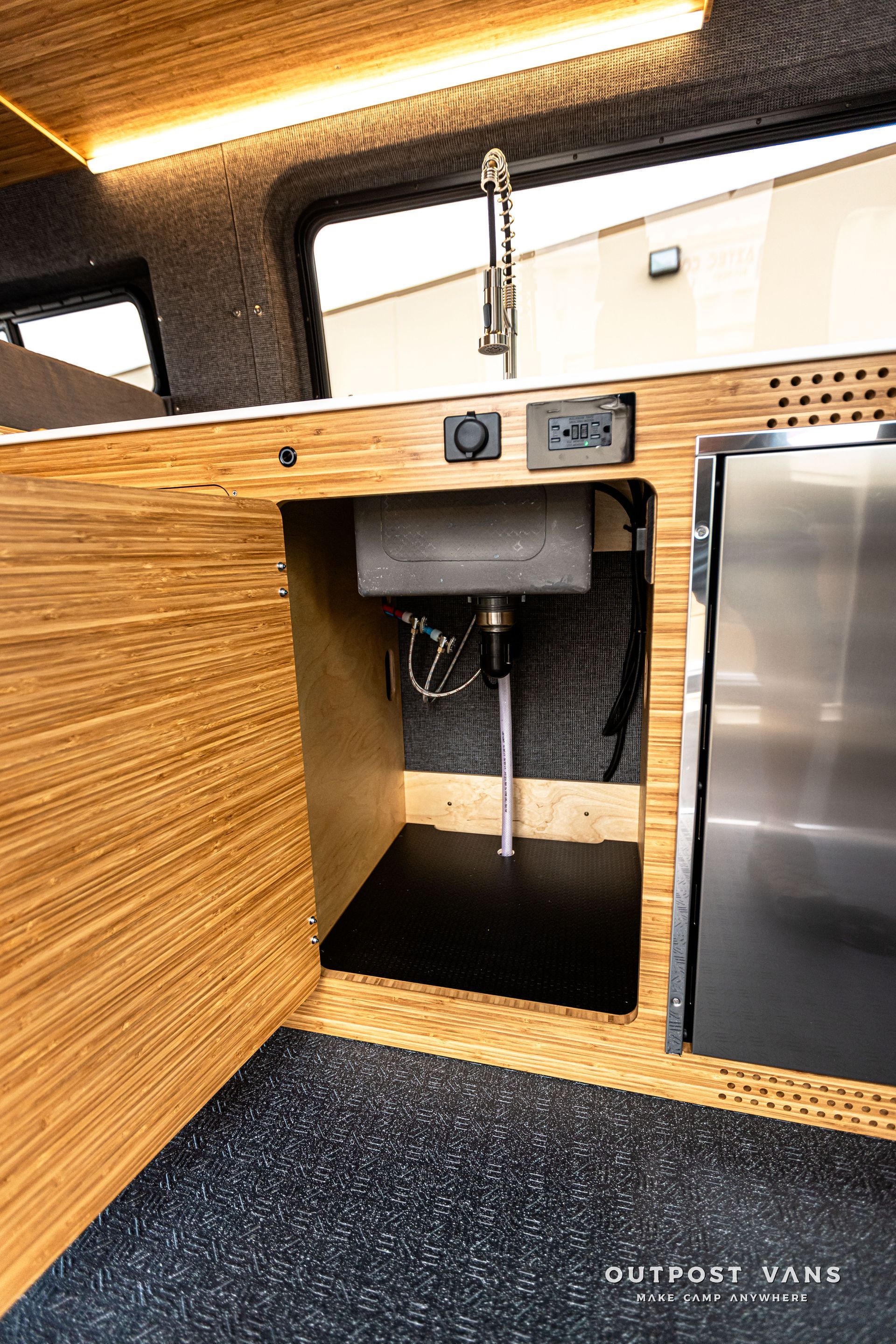A kitchen with a sink and a stainless steel refrigerator.