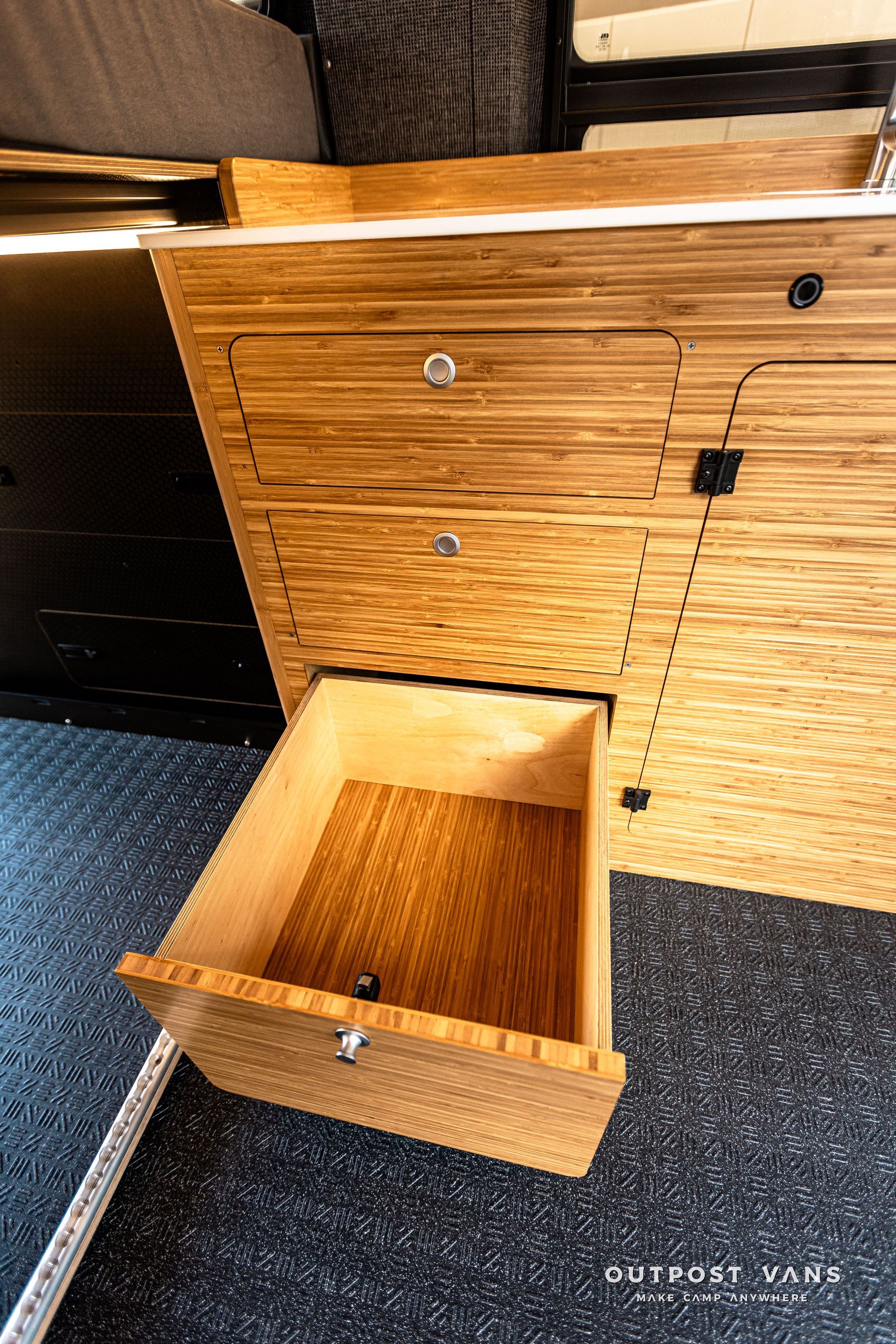 A wooden drawer is open in a wooden cabinet.