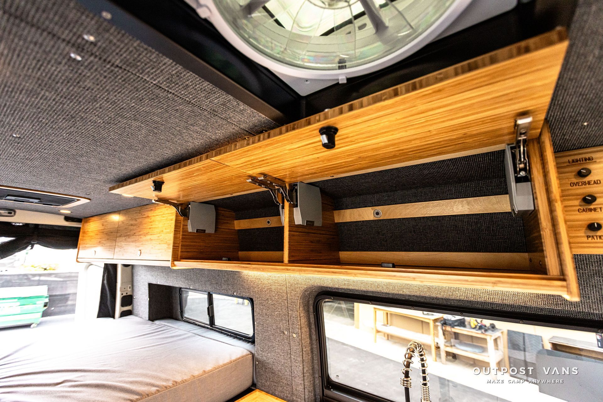 A camper van with a bed and a fan on the ceiling.