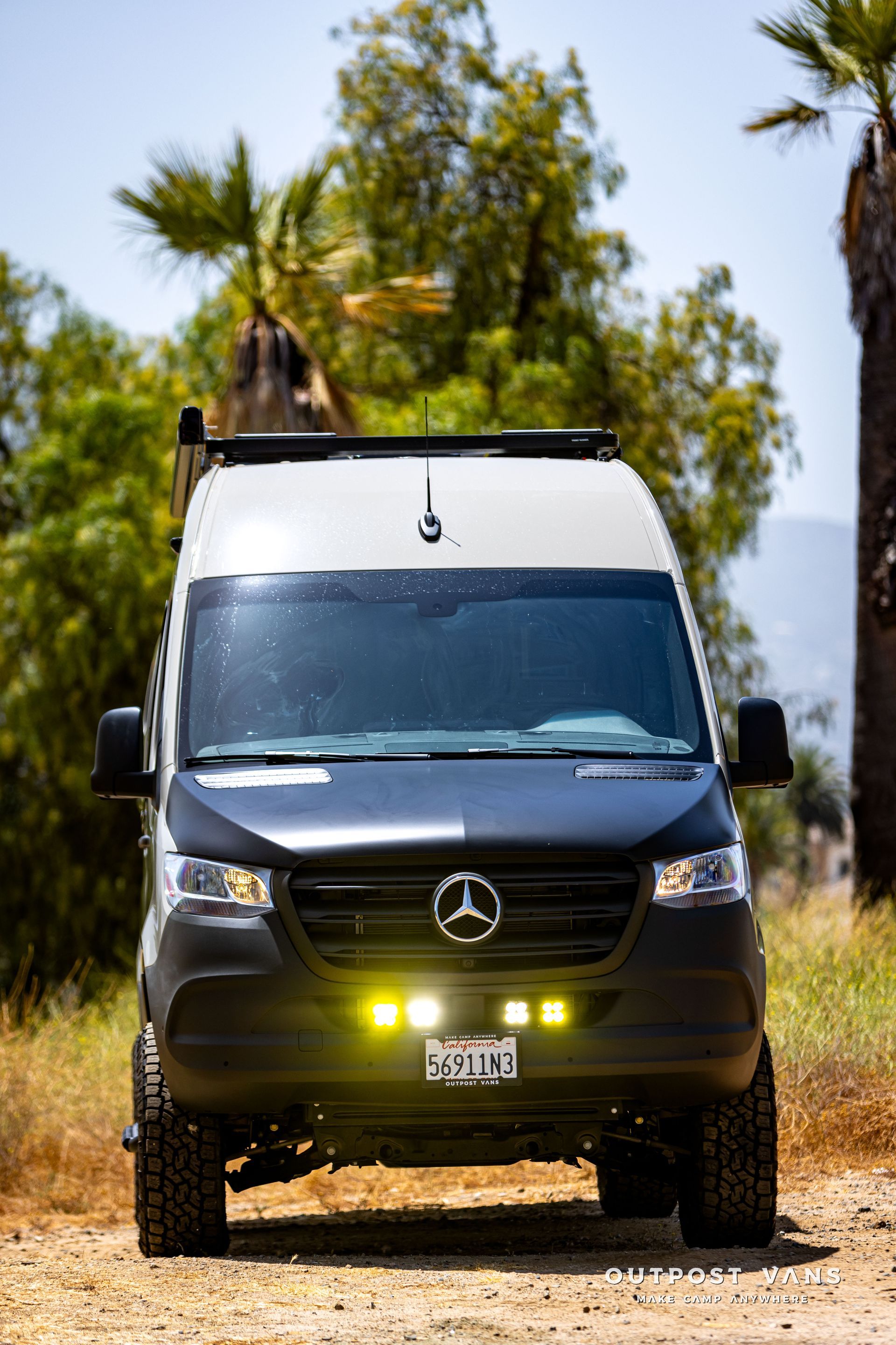 A black and white van is parked on a dirt road.